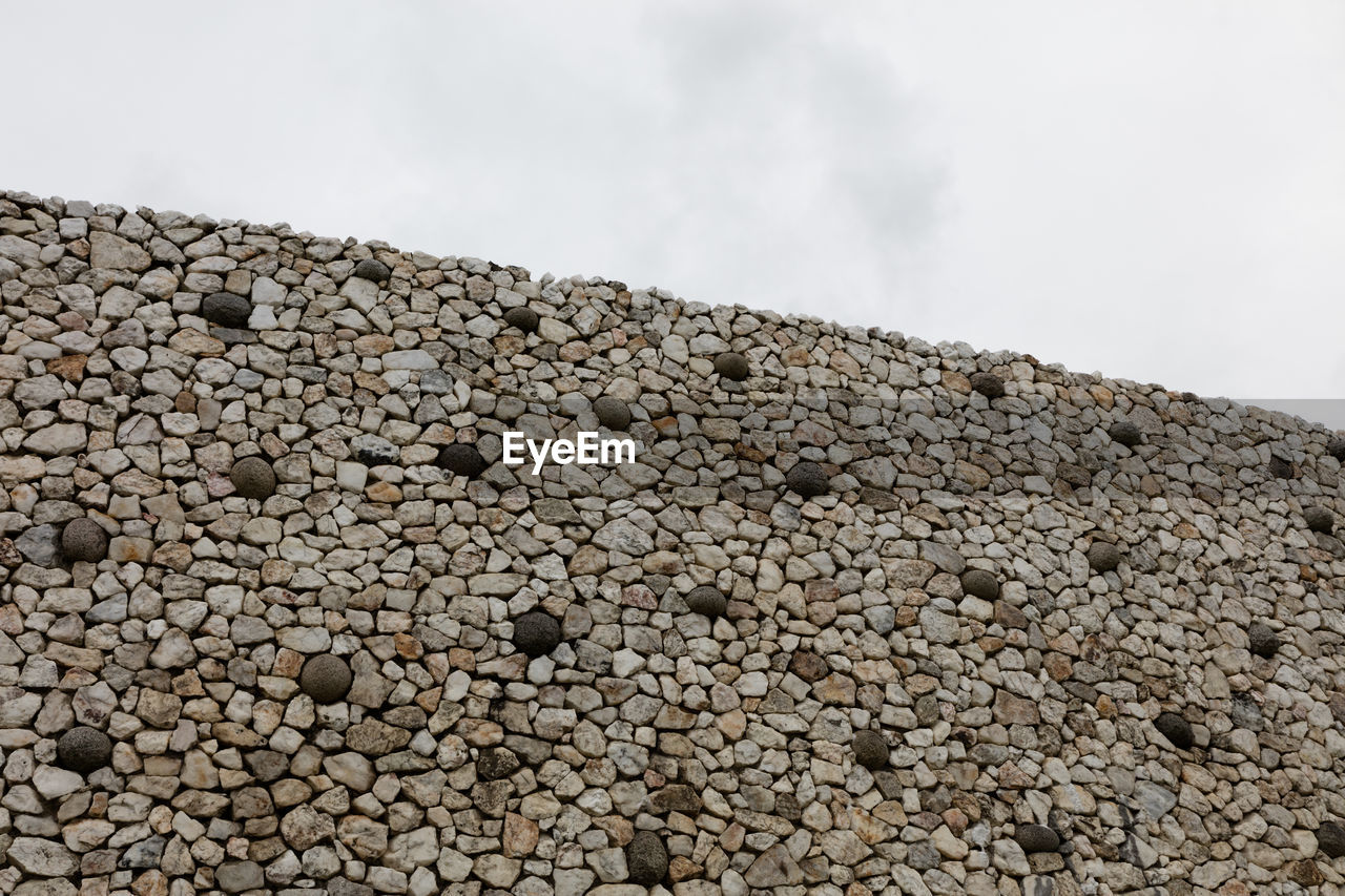 CLOSE-UP OF STONE WALL AGAINST SKY