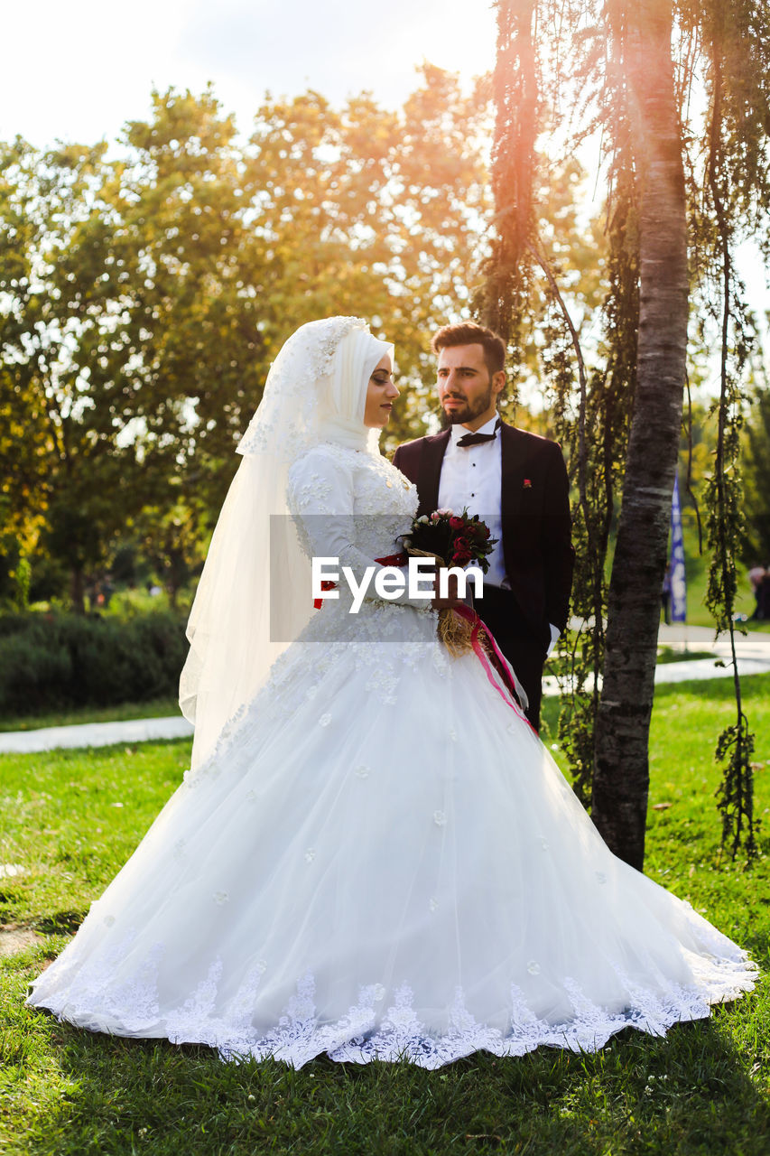 Bride and bridegroom standing at park