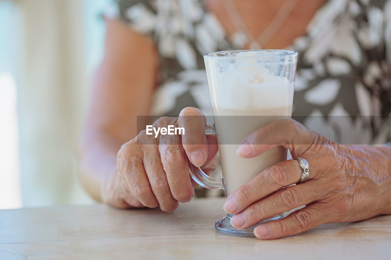 Cropped photo of senior woman holding cup of coffee outdoors