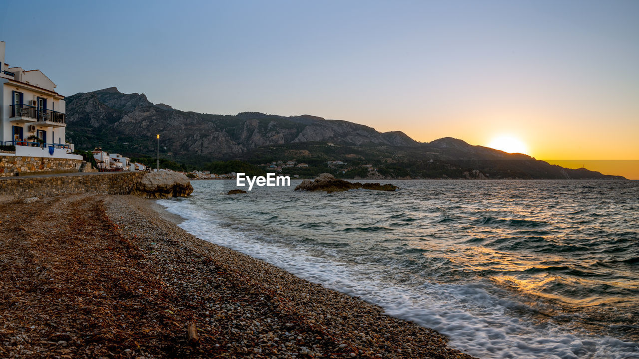 water, sky, coast, sea, shore, body of water, land, beach, ocean, nature, horizon, architecture, morning, scenics - nature, wave, beauty in nature, dusk, travel destinations, building exterior, mountain, built structure, travel, rock, clear sky, building, coastline, environment, no people, bay, landscape, tranquility, sand, sunrise, city, outdoors, tourism, cloud, sunlight, motion, holiday, vacation, trip, tranquil scene, sun, idyllic, seascape, house, terrain