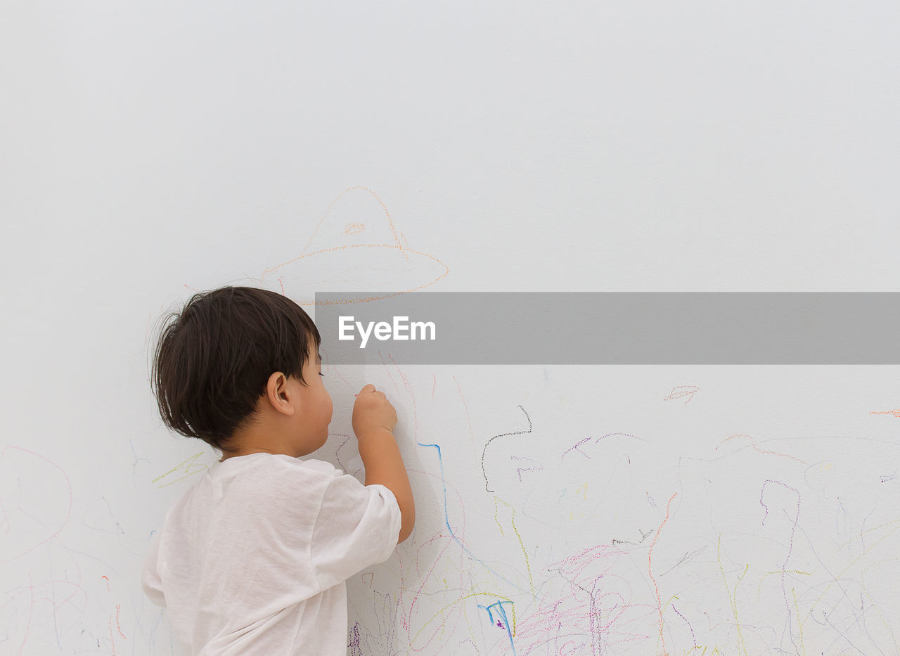 Rear view of boy writing on wall