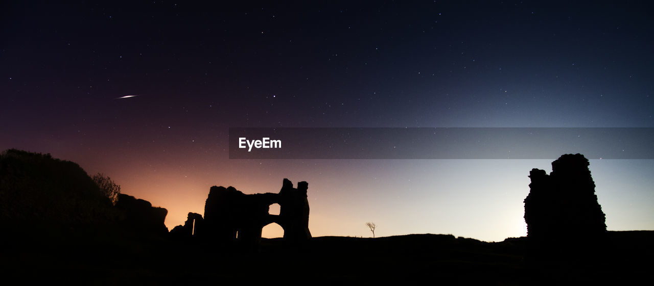 Panoramic view of silhouette built structure against sky at night