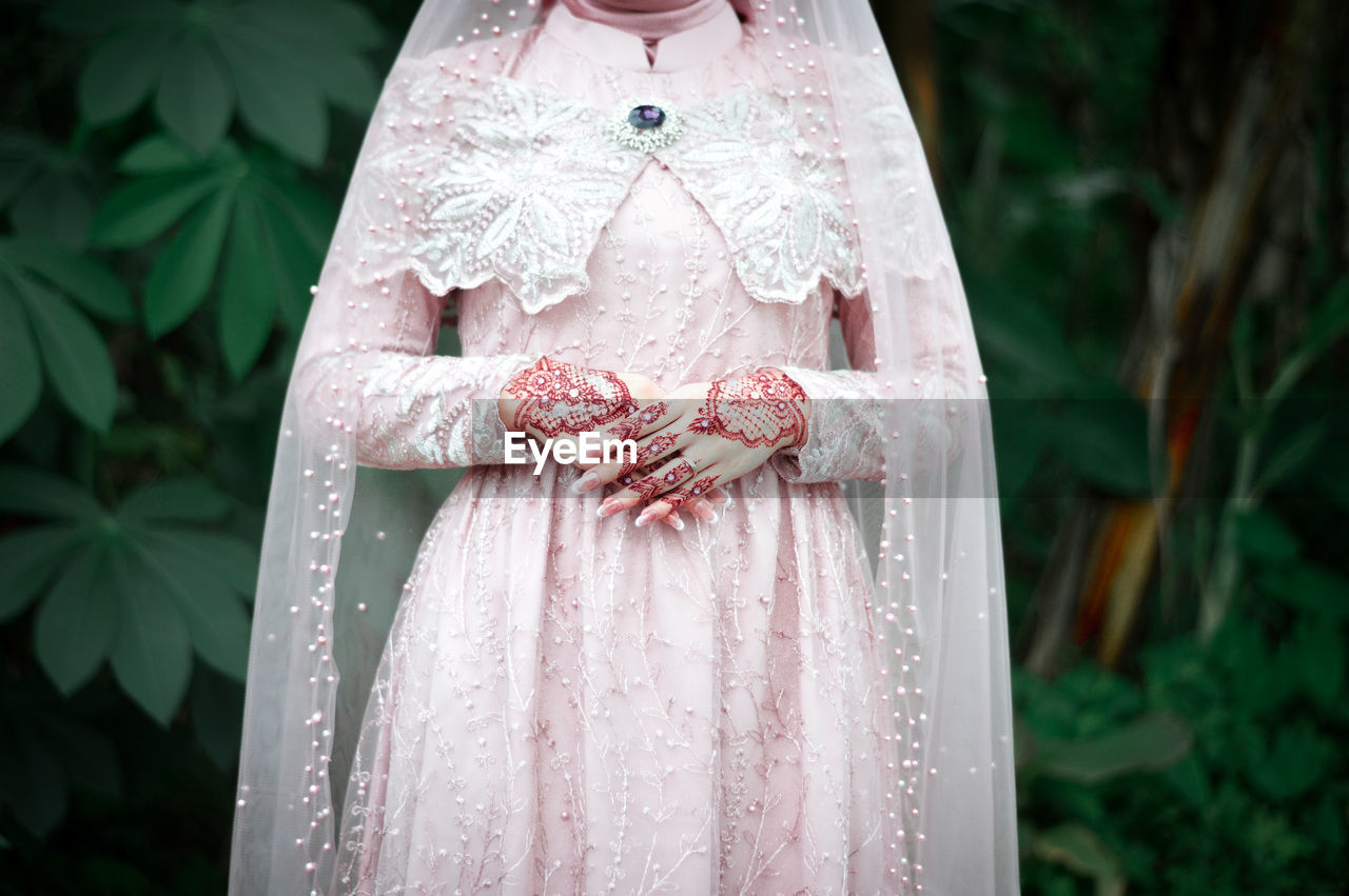 Close-up of woman standing by pink dress