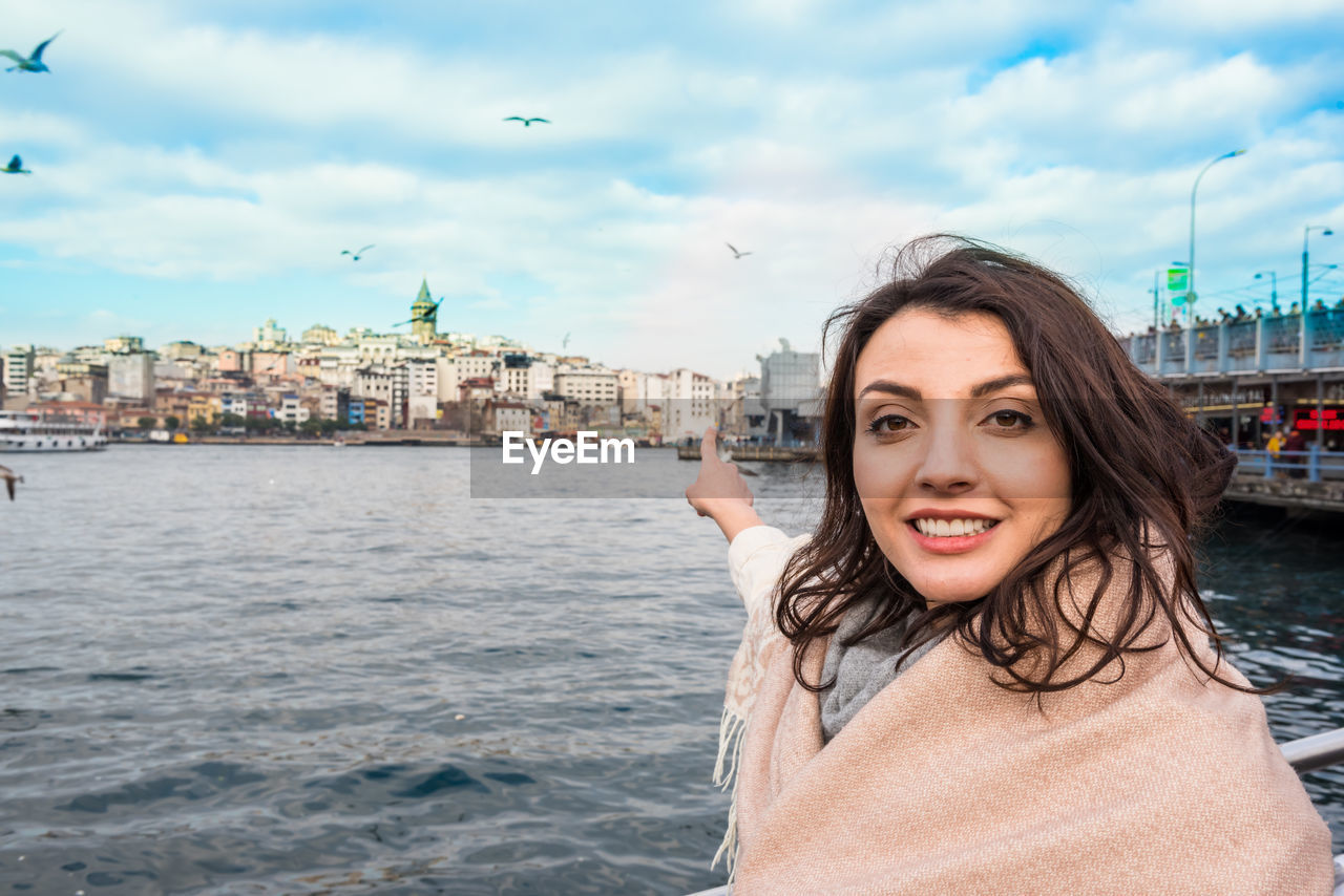 PORTRAIT OF HAPPY WOMAN AGAINST SKY