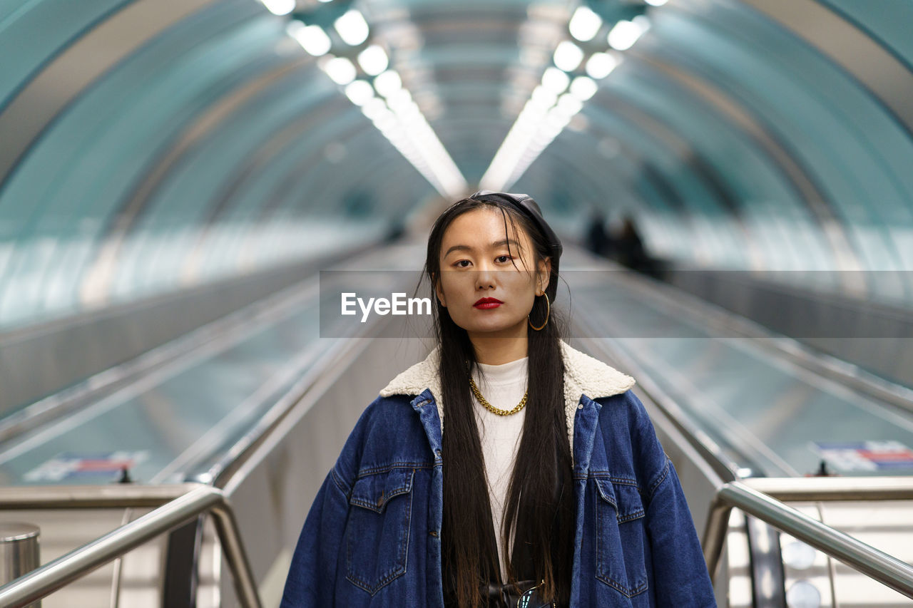 Asian girl street fashion look, stylish female wearing leather beret on escalator ride to subway
