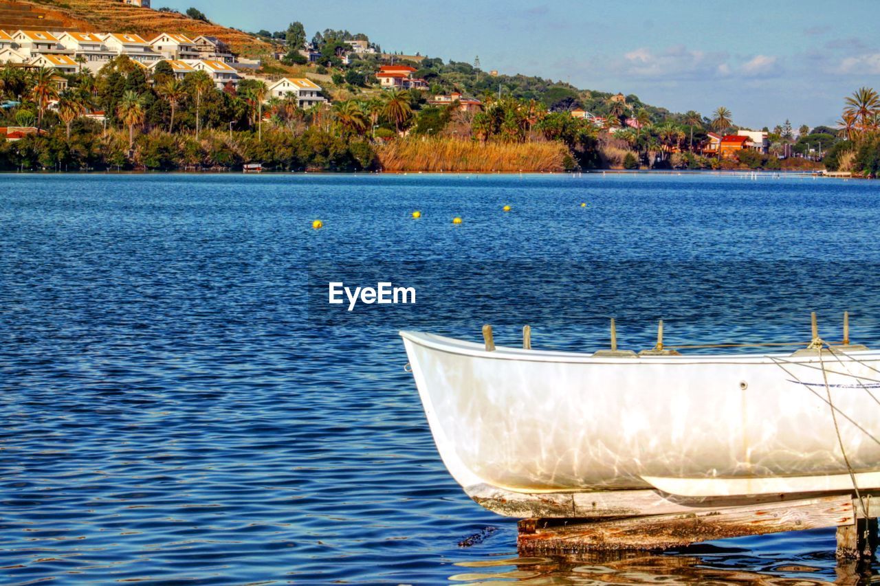 BOAT IN SEA BY TREES AGAINST SKY