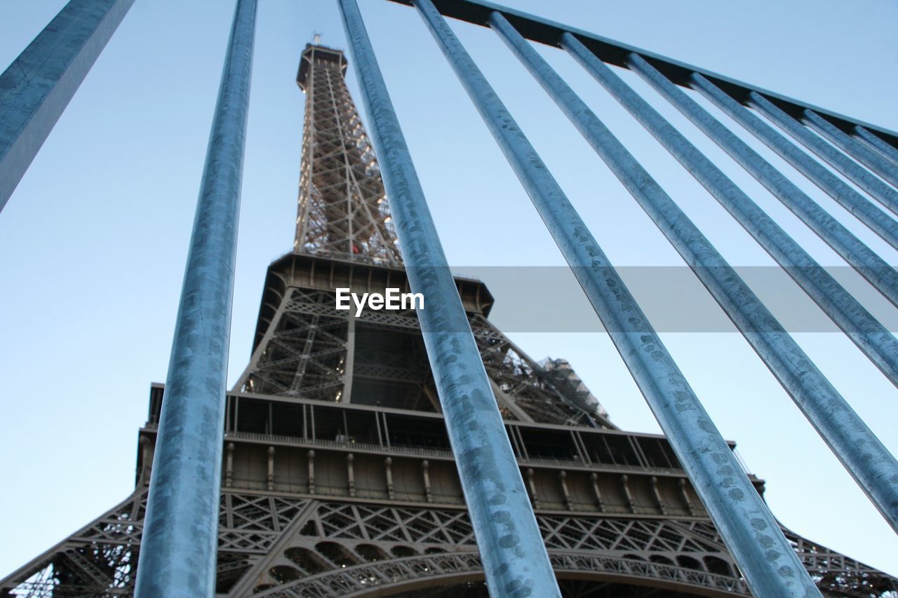 Low angle view of eiffel tower seen through railing against sky