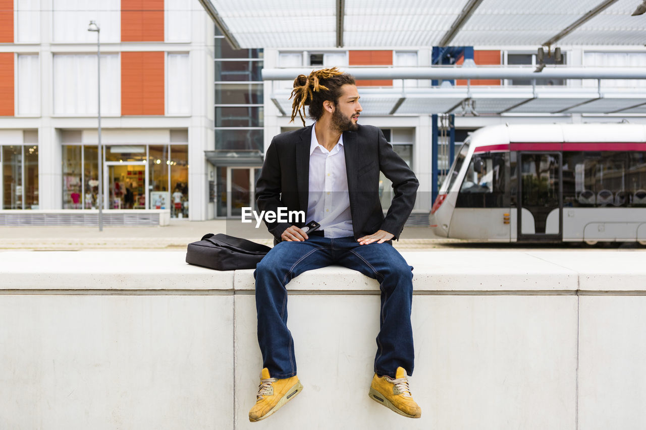 Young businessman with dreadlocks waiting at station