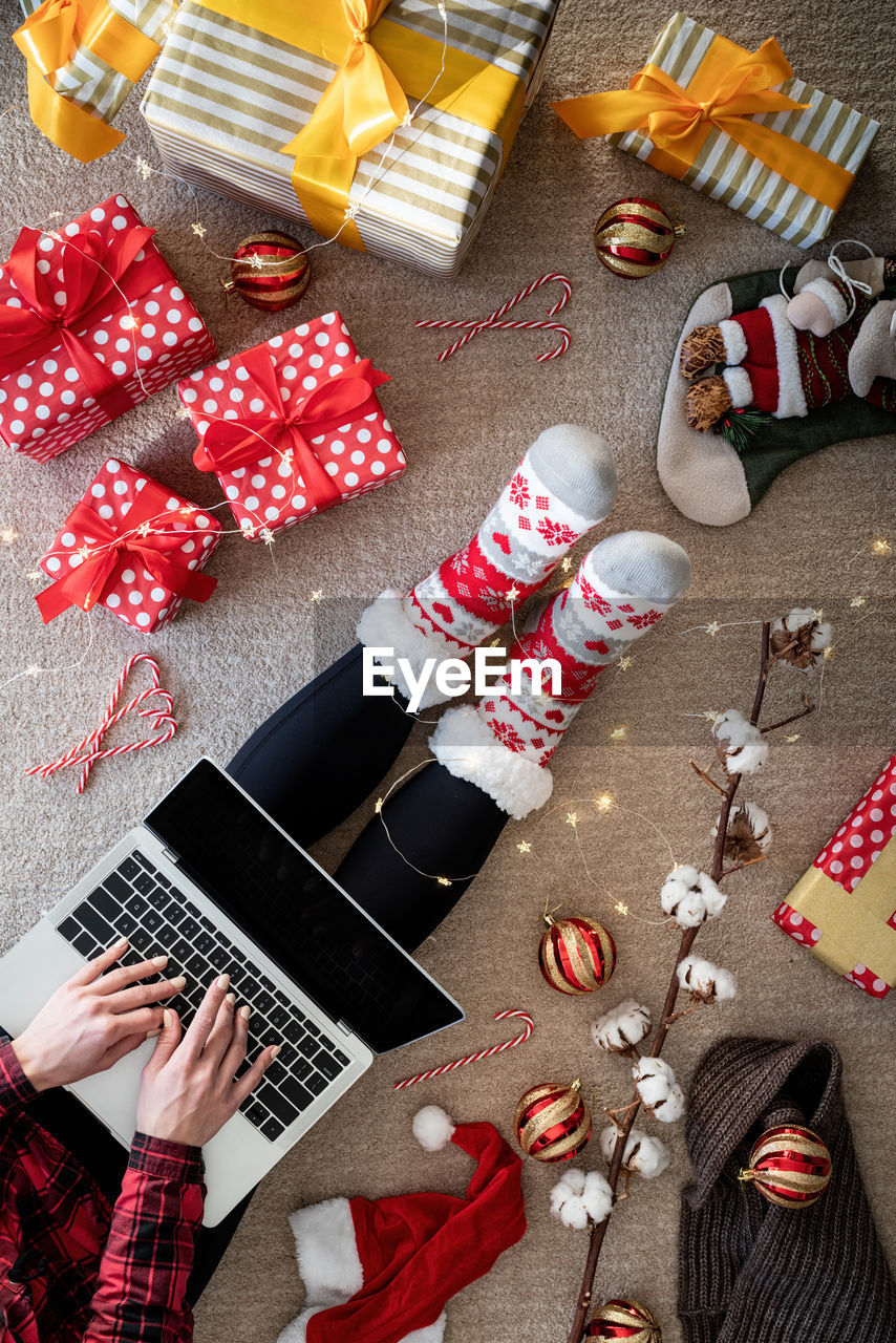 Directly above shot of young woman using laptop by christmas decoration