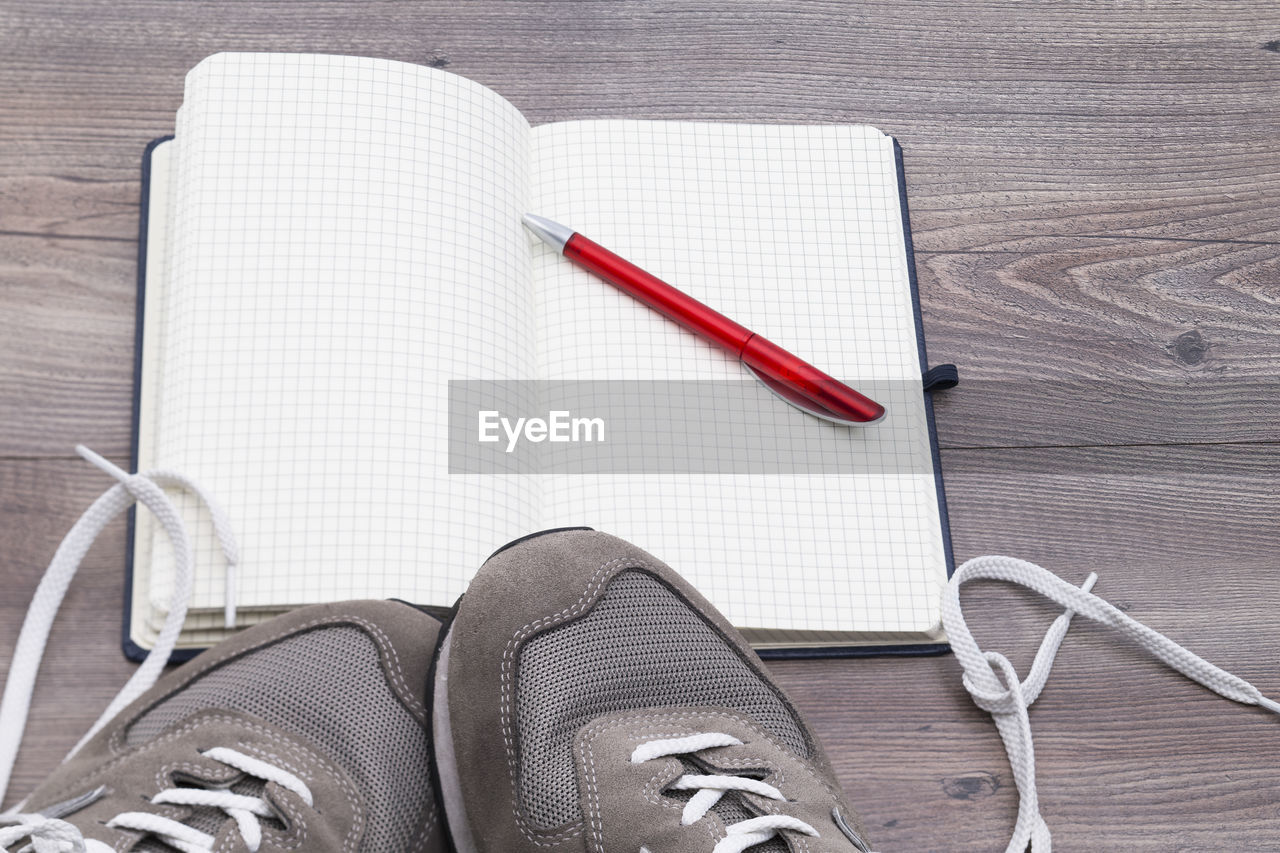 High angle view of pen and book with shoes on table