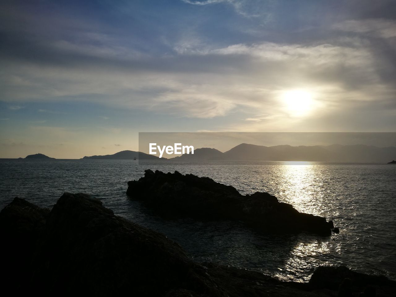 SCENIC VIEW OF SEA BY SILHOUETTE MOUNTAIN AGAINST SKY