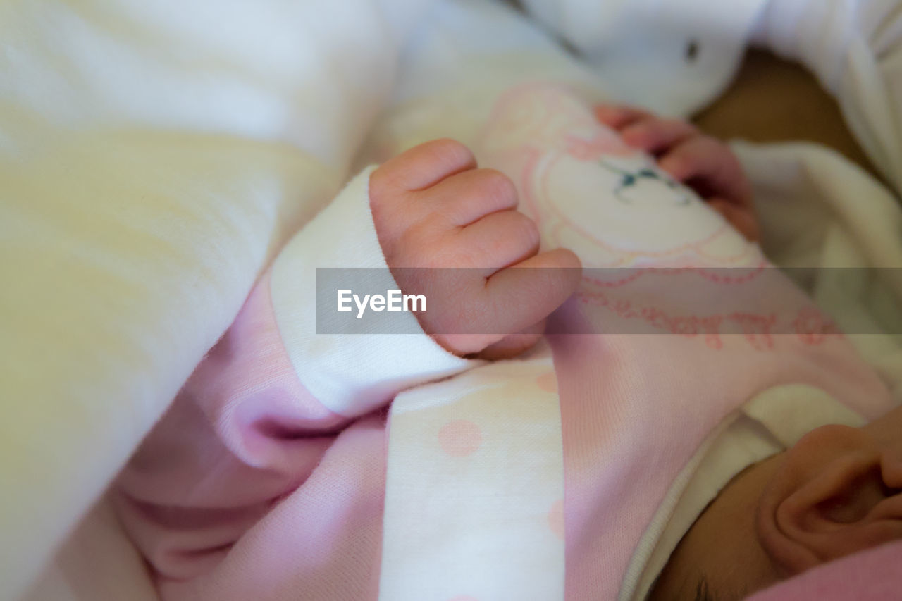 Midsection of baby girl lying on bed