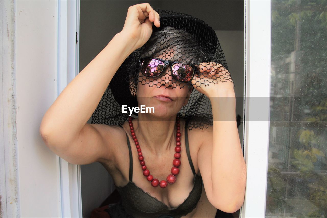 Portrait of sensuous mature woman wearing hat and sunglasses