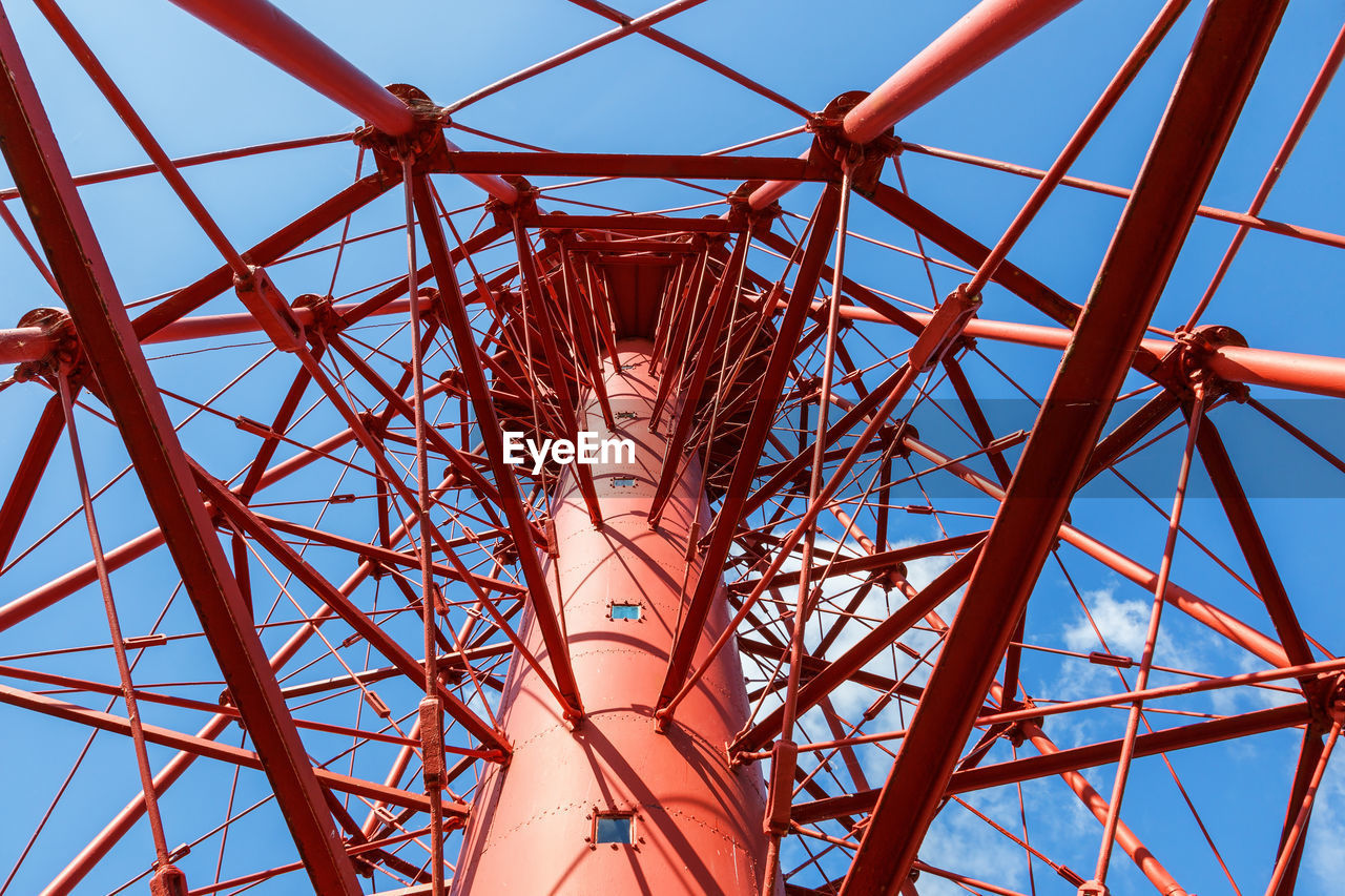 Red cast iron lighthouse against a blue sky from below