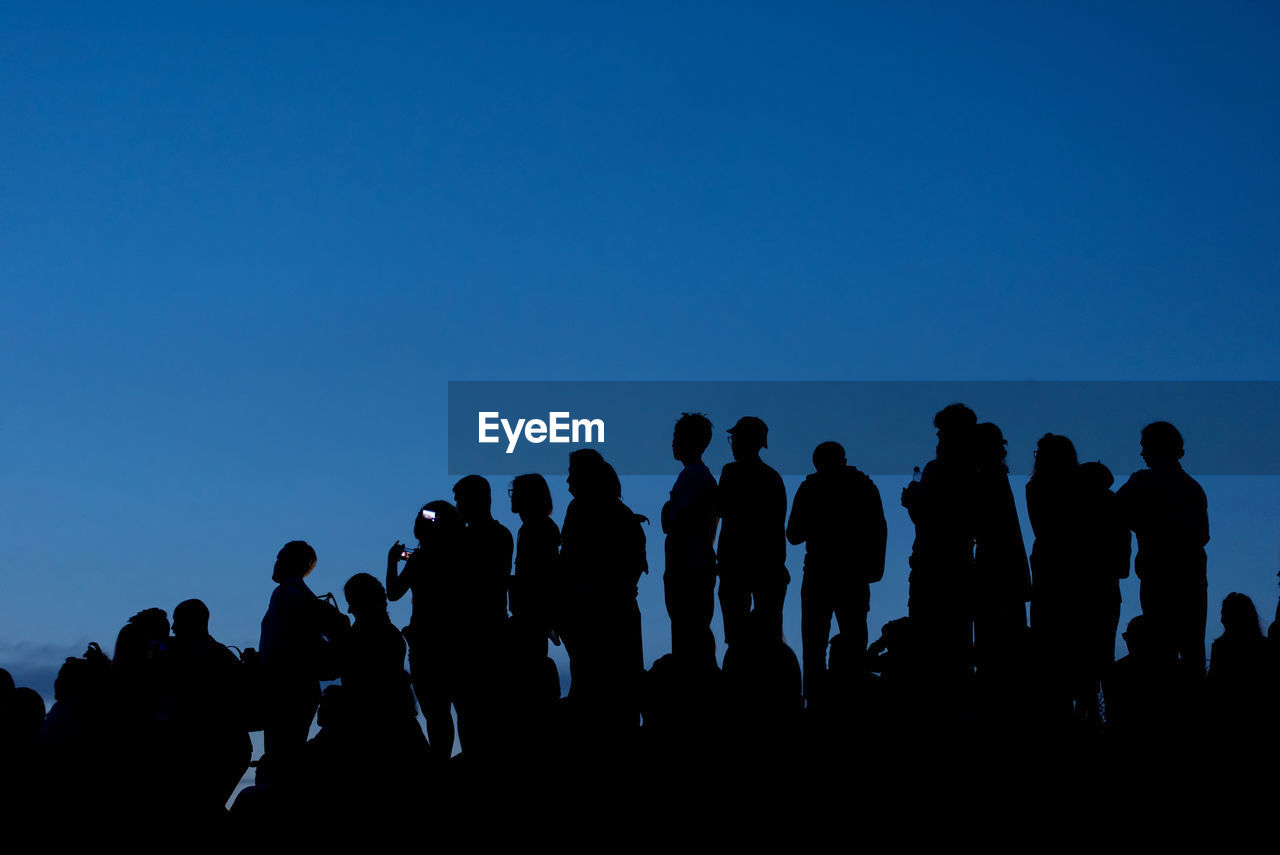 Silhouette people against clear blue sky