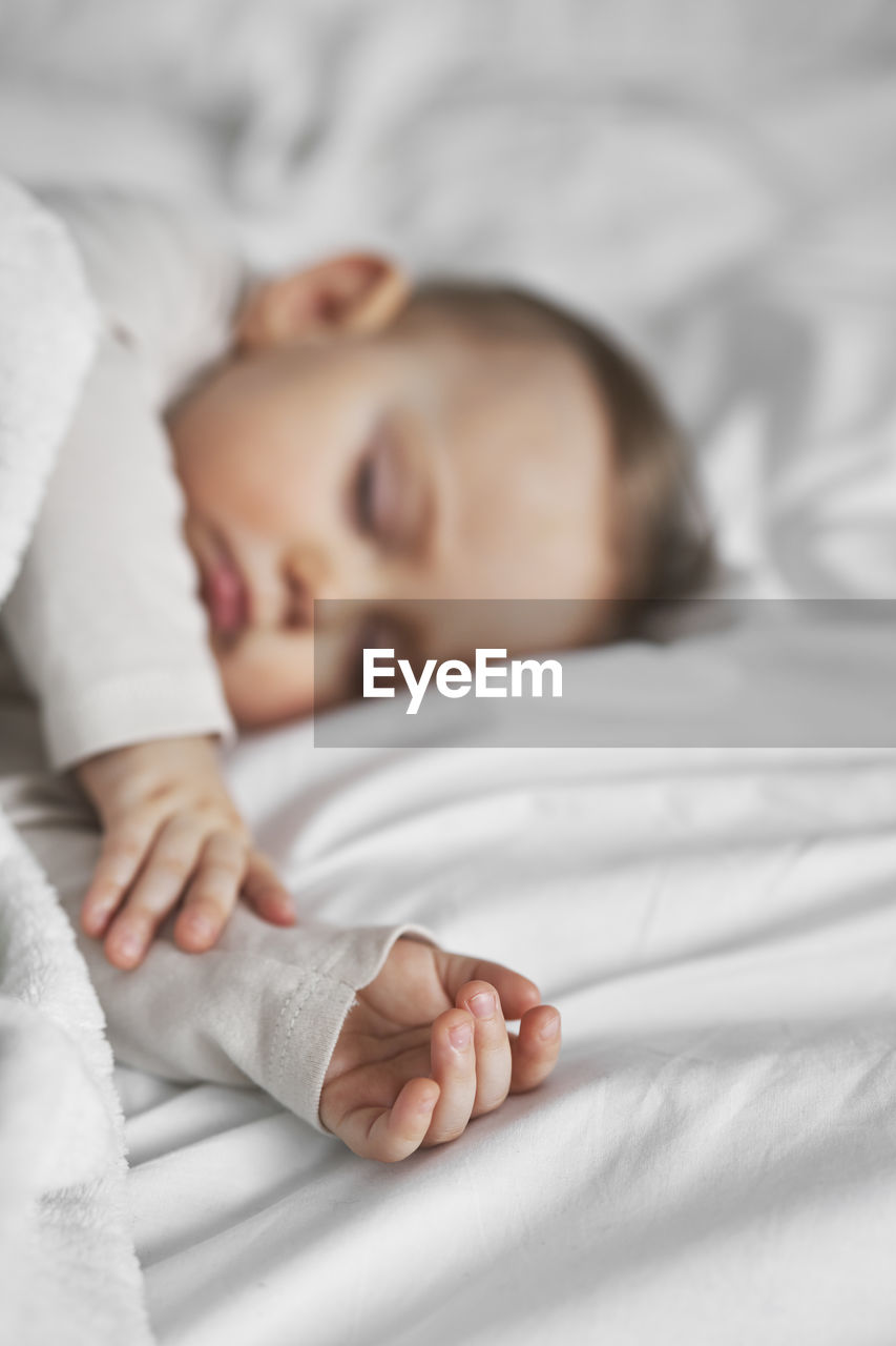 Close-up of cute baby boy lying on bed at home