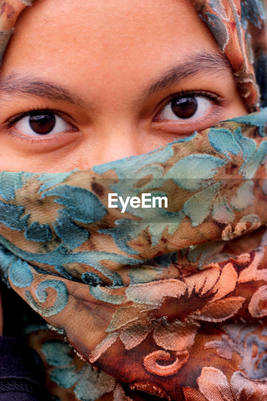 Close-up portrait of woman face covered with scarf