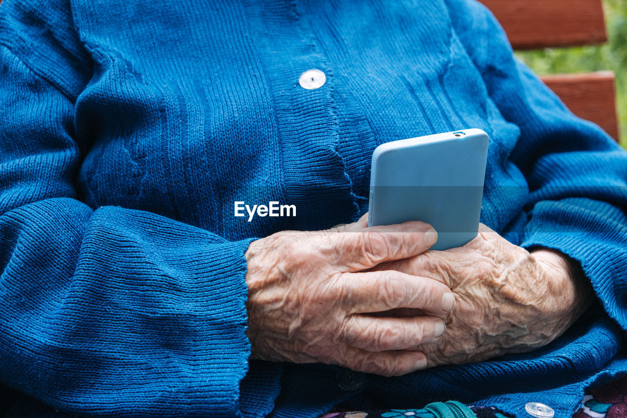 Senior mature woman, grandmother holding phone, using mobile device apps, looking at screen