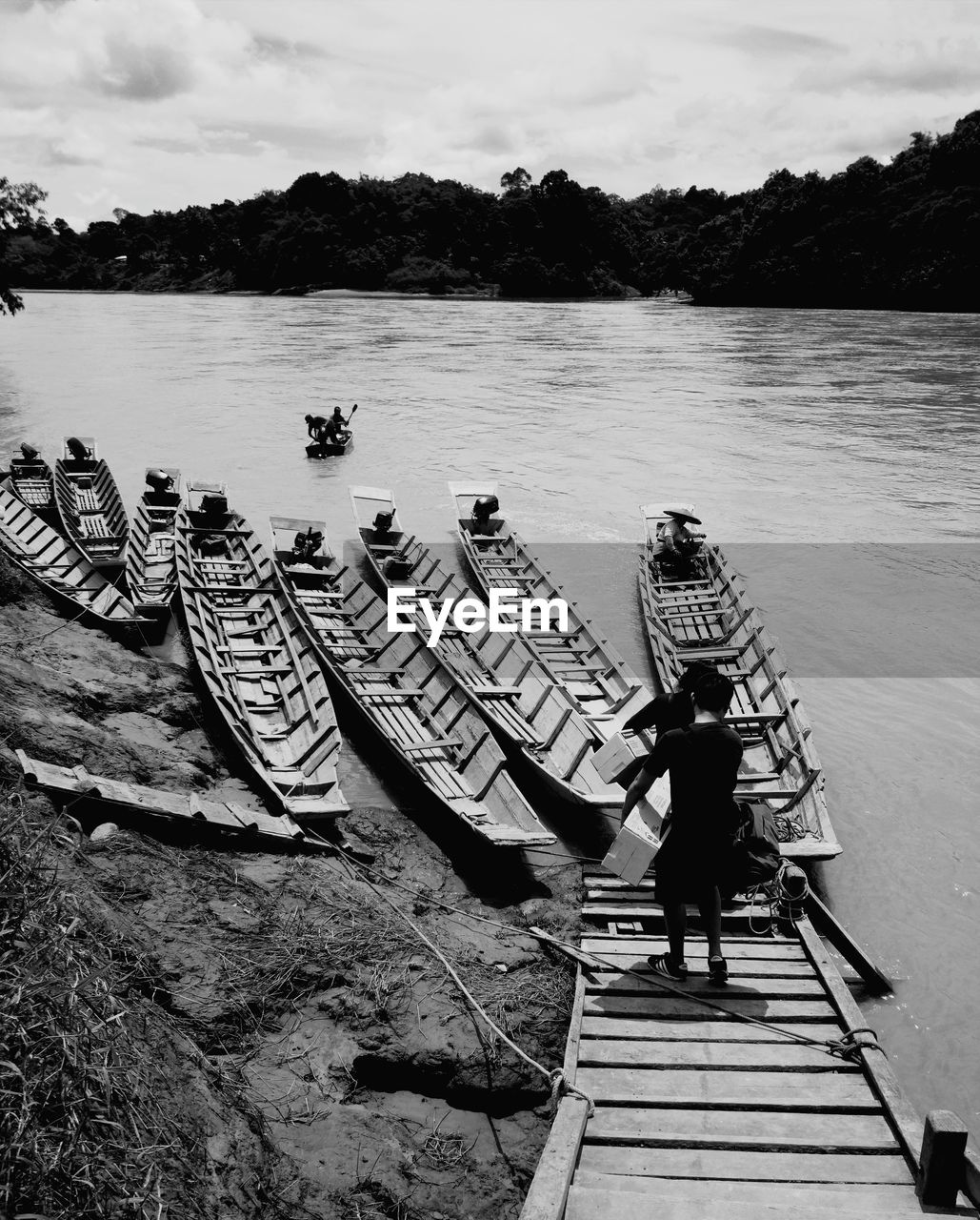 Rear view of man on pier at lake against sky