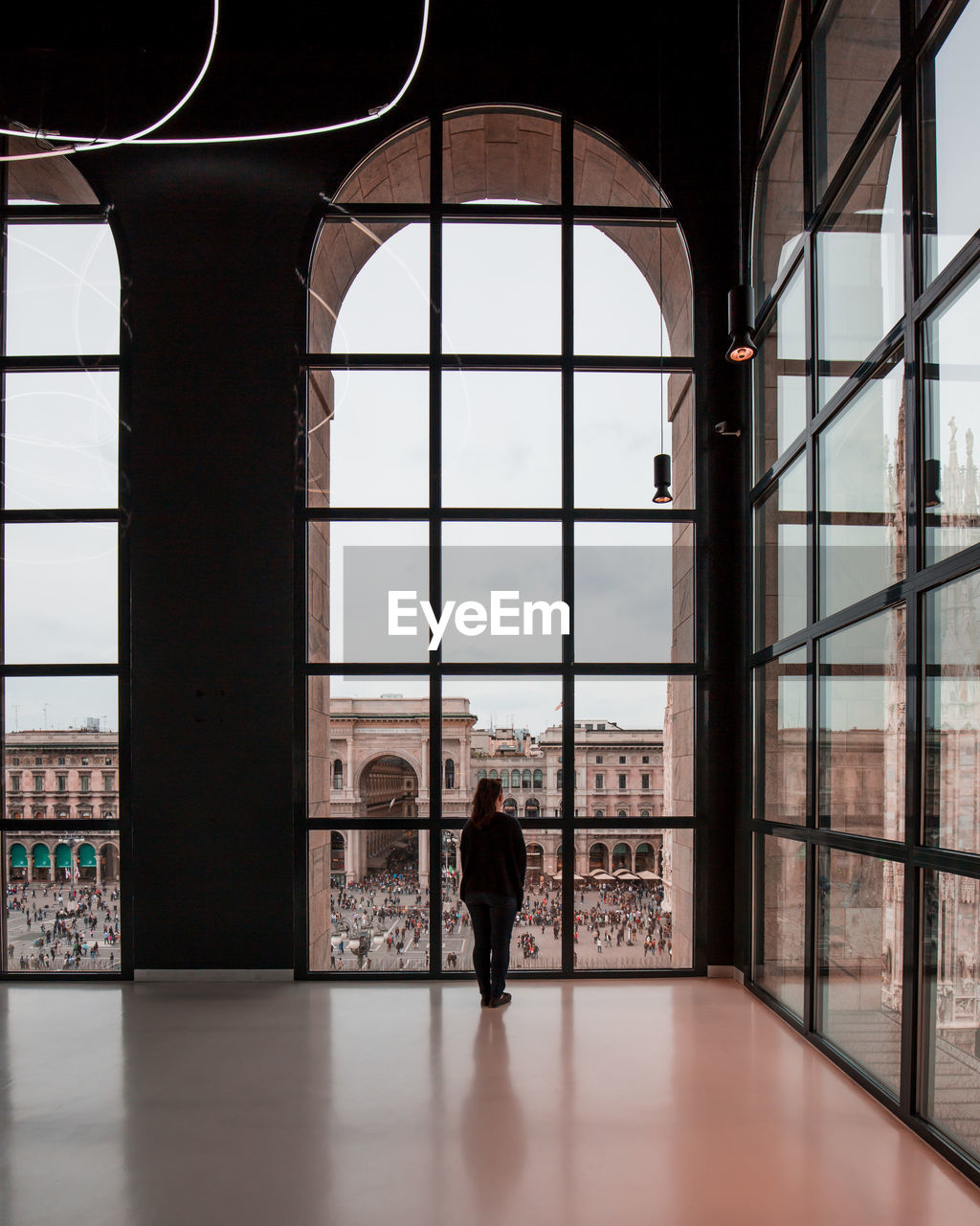 Woman looking at piazza del duomo through glass window