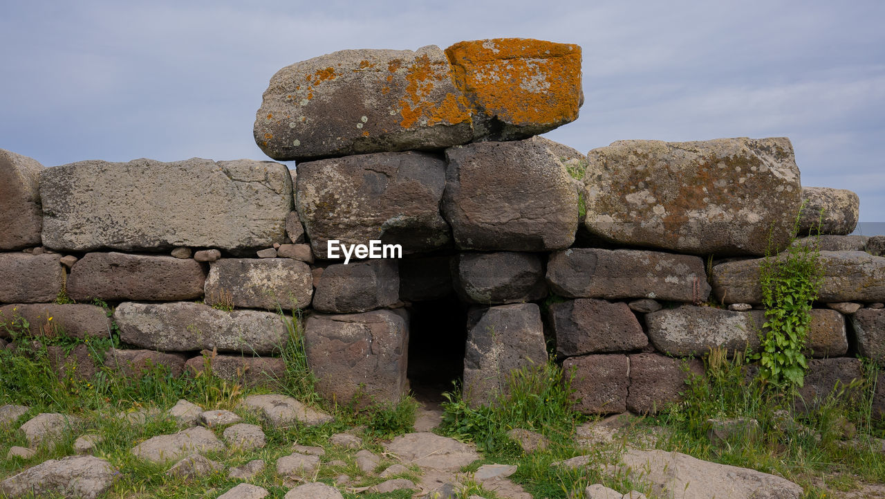 rock, wall, ruins, nature, ancient history, sky, architecture, boulder, no people, history, stone material, stone, outdoors, the past, land, stone wall, ancient, cloud, built structure, travel destinations, plant, old ruin, landscape, megalith, travel, day, environment, terrain