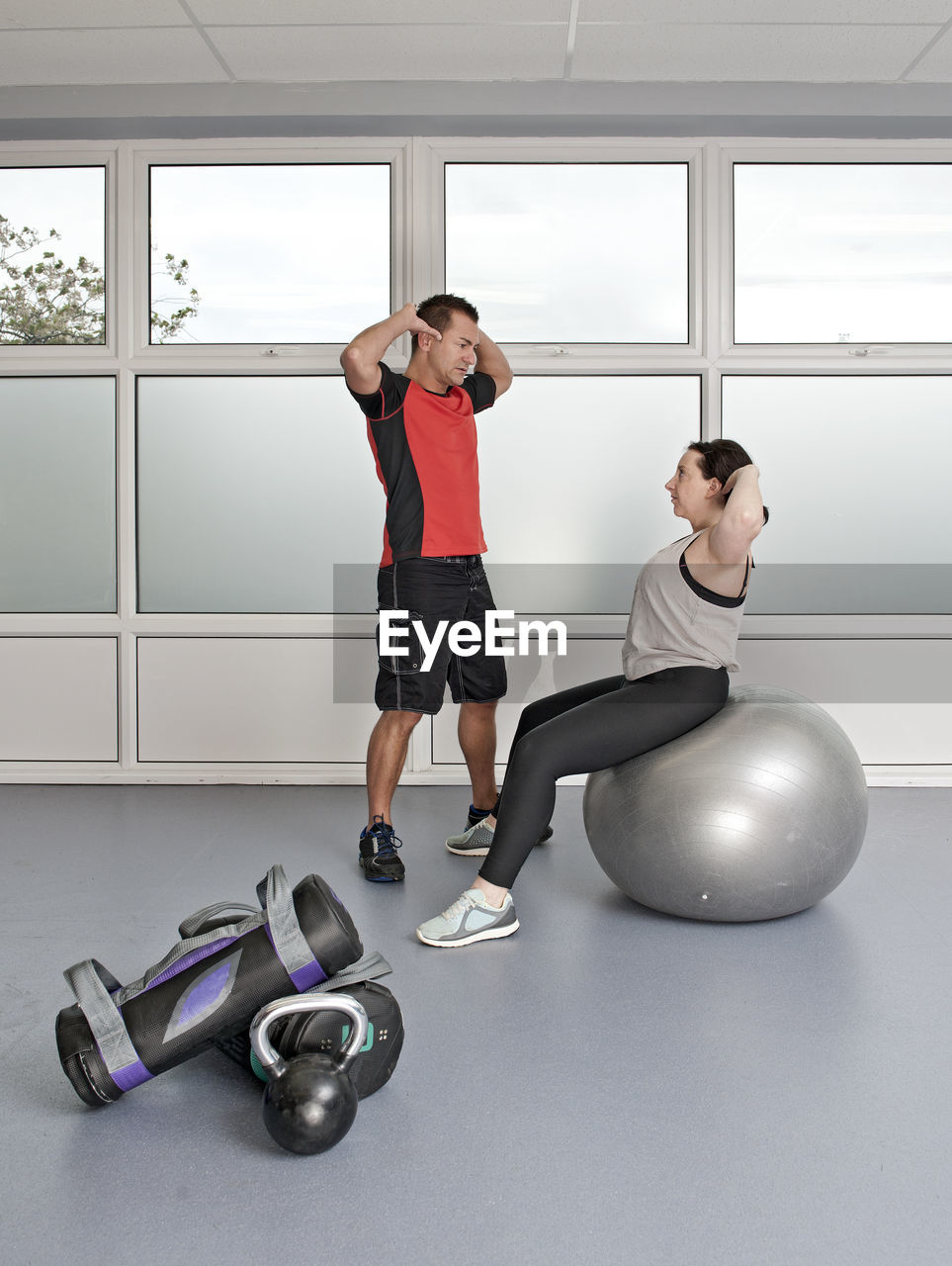 Personal trainer helping client at gym in the uk