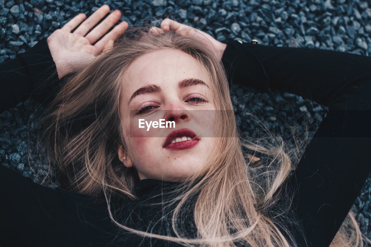 Portrait of young woman lying on rocks