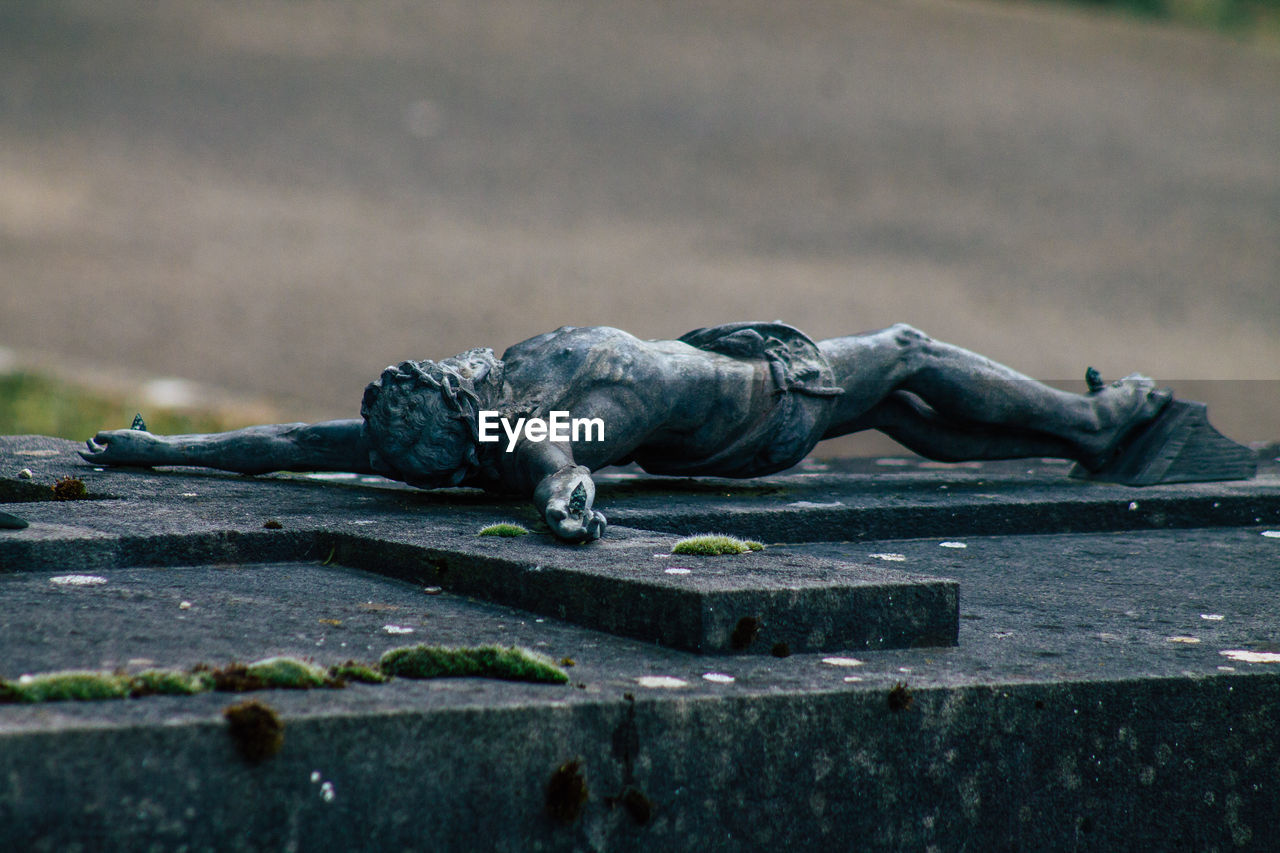 CLOSE-UP OF OLD STATUE AGAINST WOODEN POST