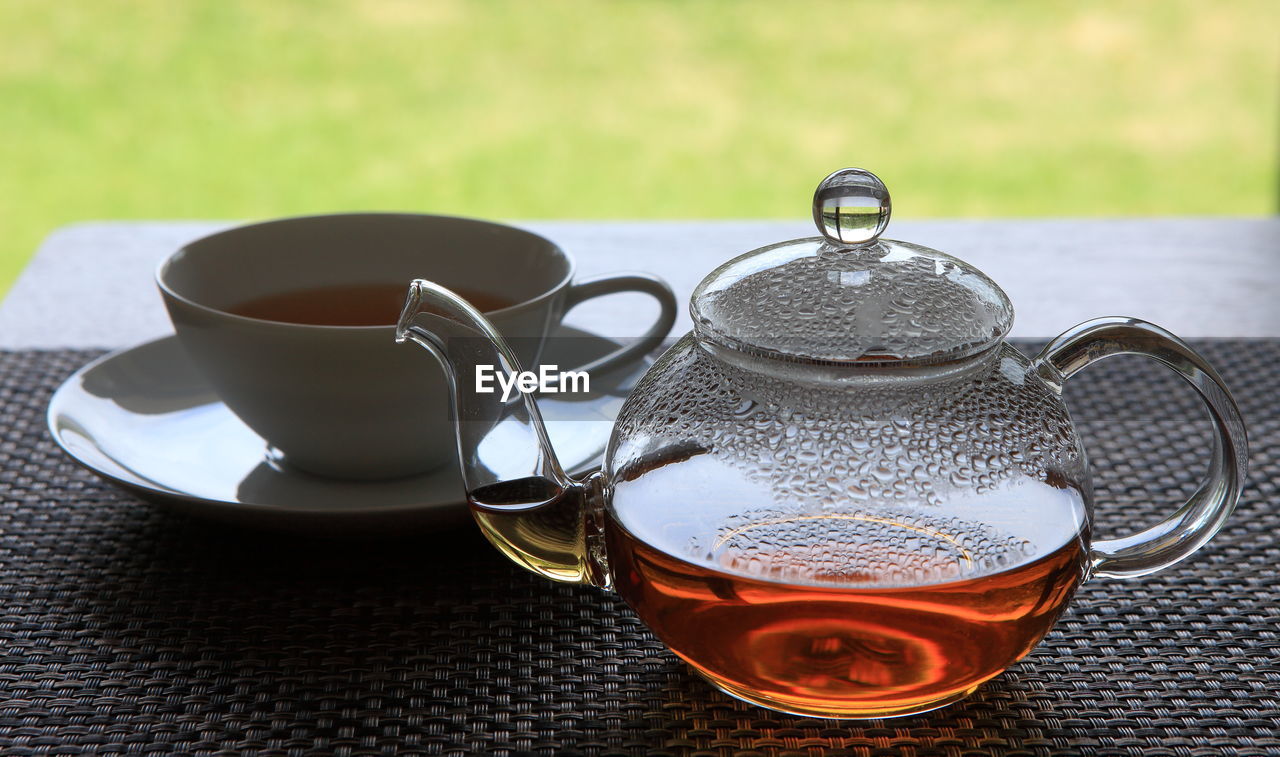 Close-up of tea cup and glass pot on table