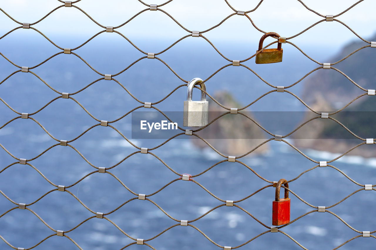 FULL FRAME SHOT OF CHAINLINK FENCE AGAINST SKY SEEN THROUGH METAL CHAIN