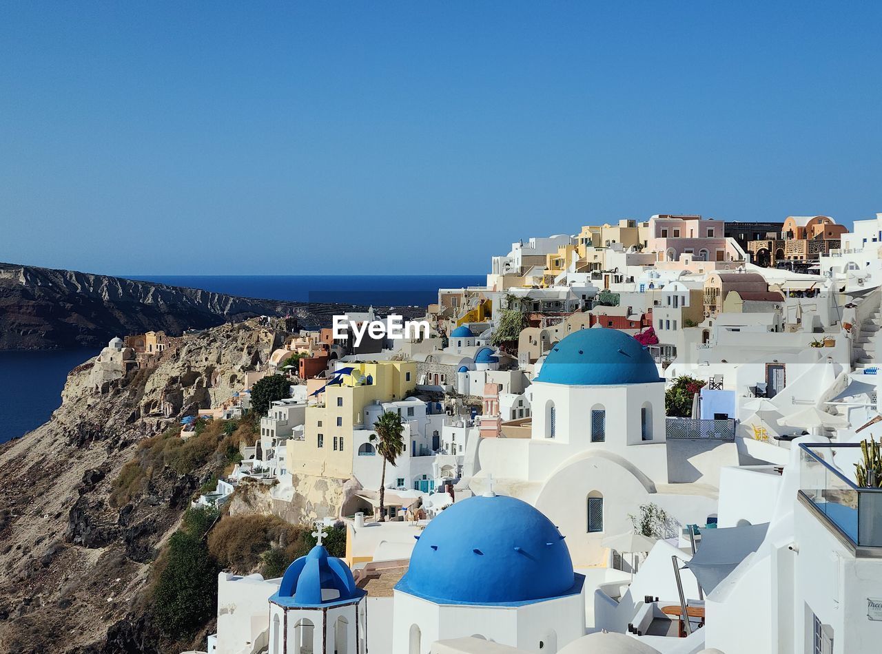 high angle view of townscape by sea against clear blue sky