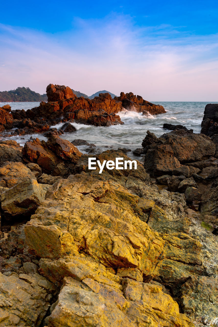 Rock formation on beach against sky during sunset