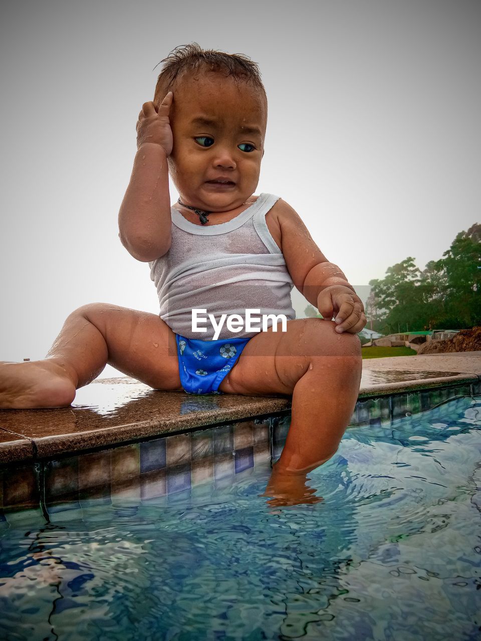 PORTRAIT OF CUTE BOY IN SWIMMING POOL AGAINST CLEAR SKY