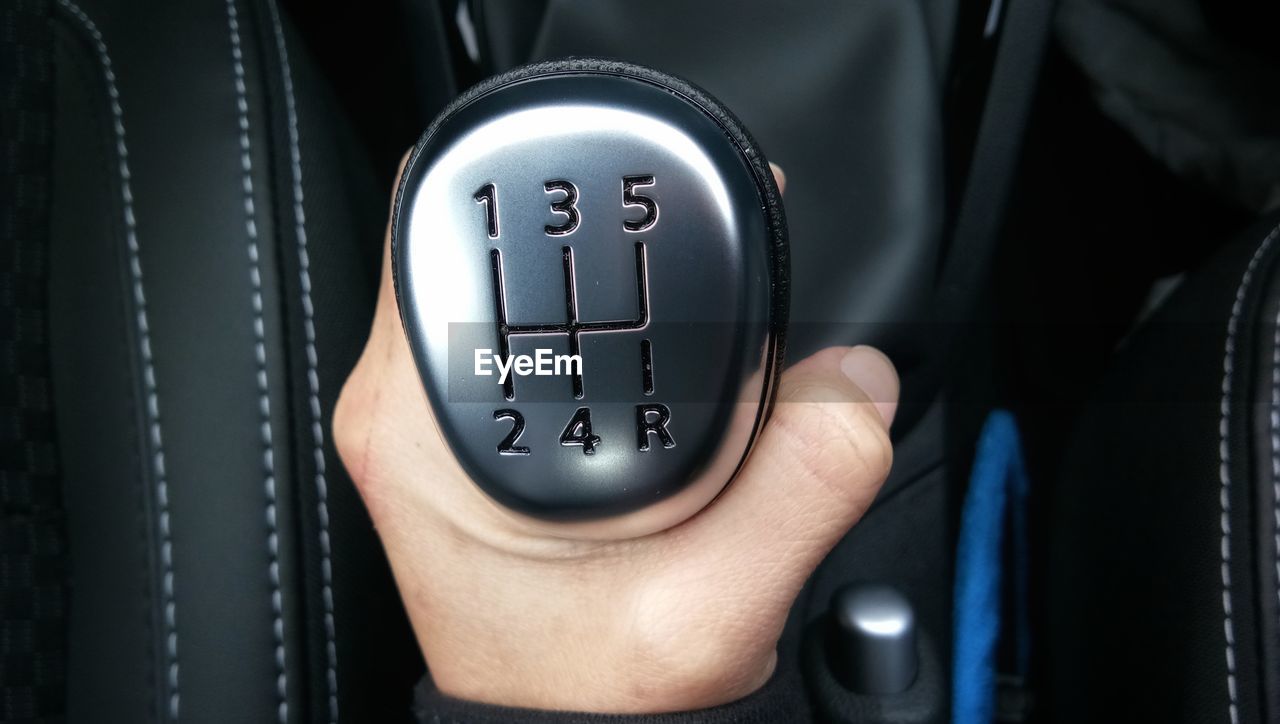 Close-up of human hand holding gearshift in car