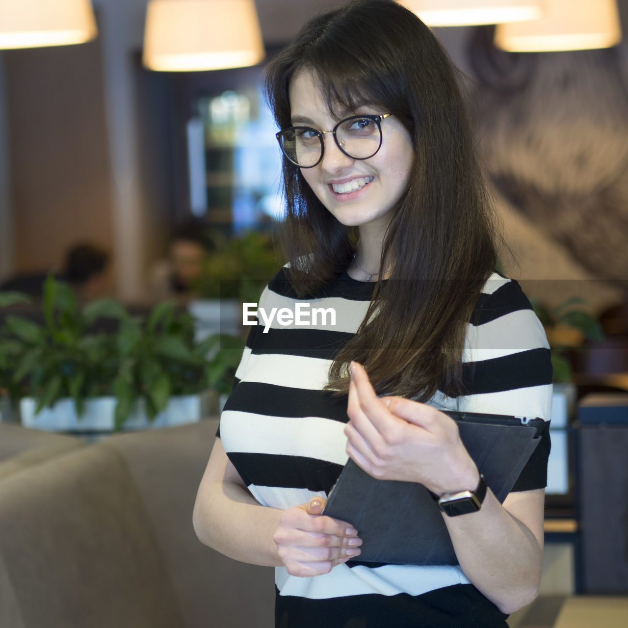 Portrait of confident young woman with digital tablet standing in restaurant