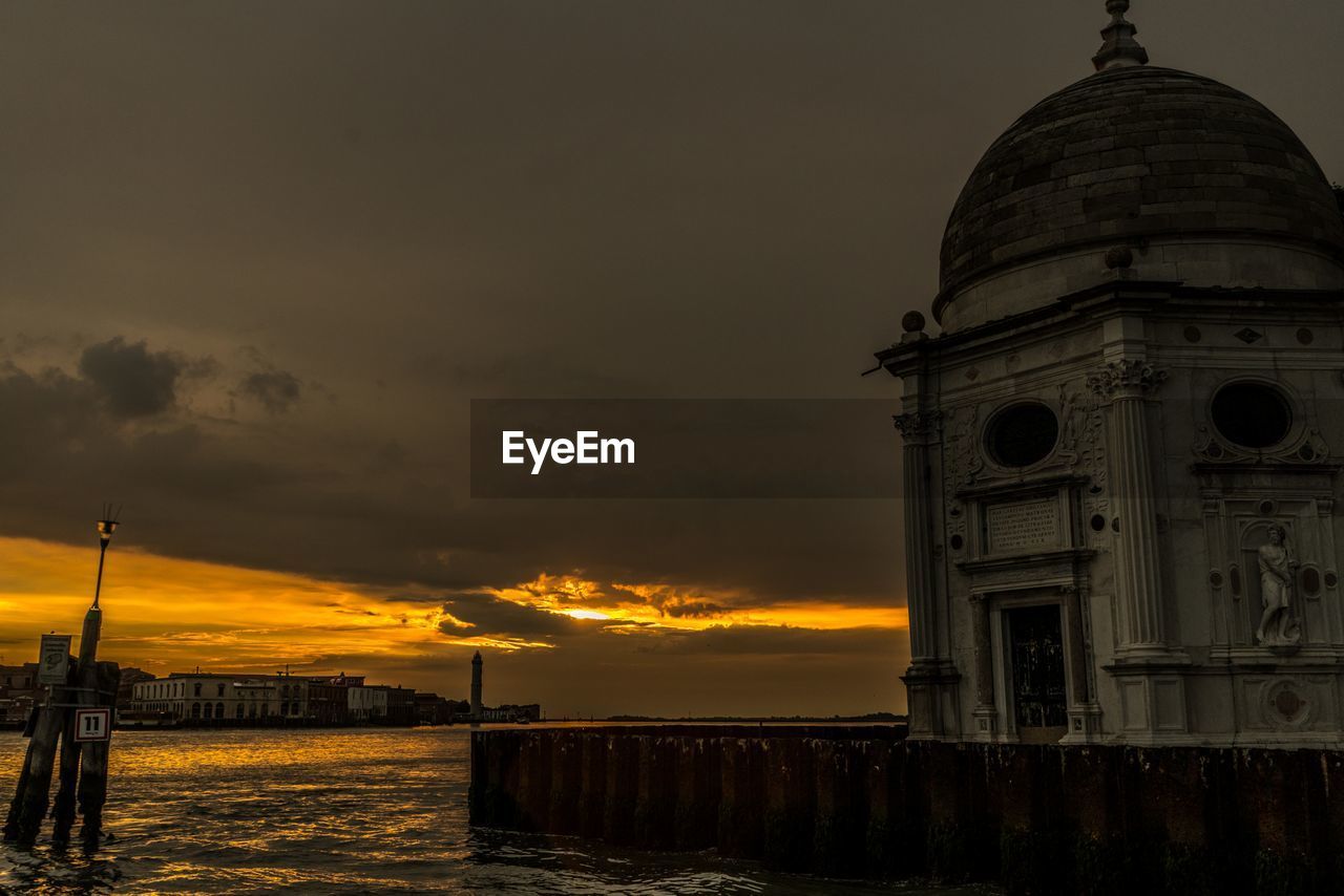 View of building by sea against sky during sunset