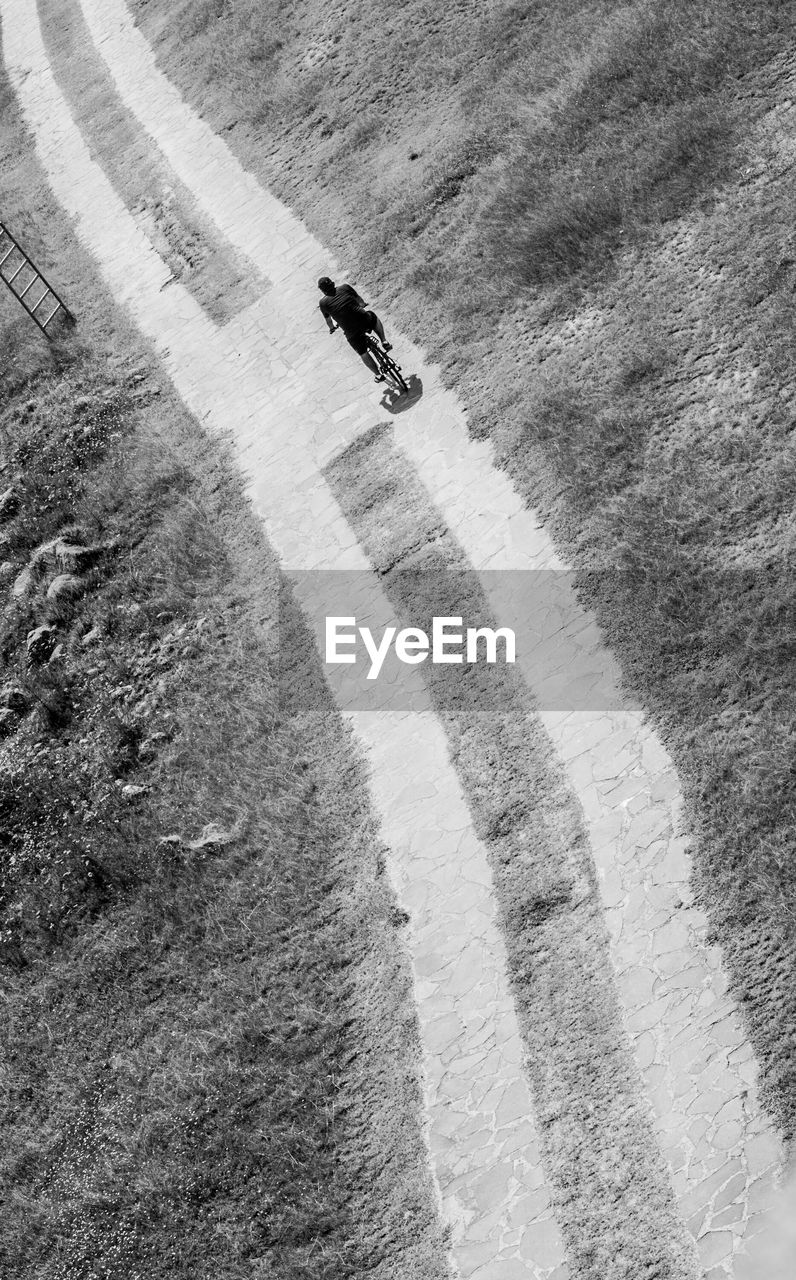High angle view of man bicycling on narrow road