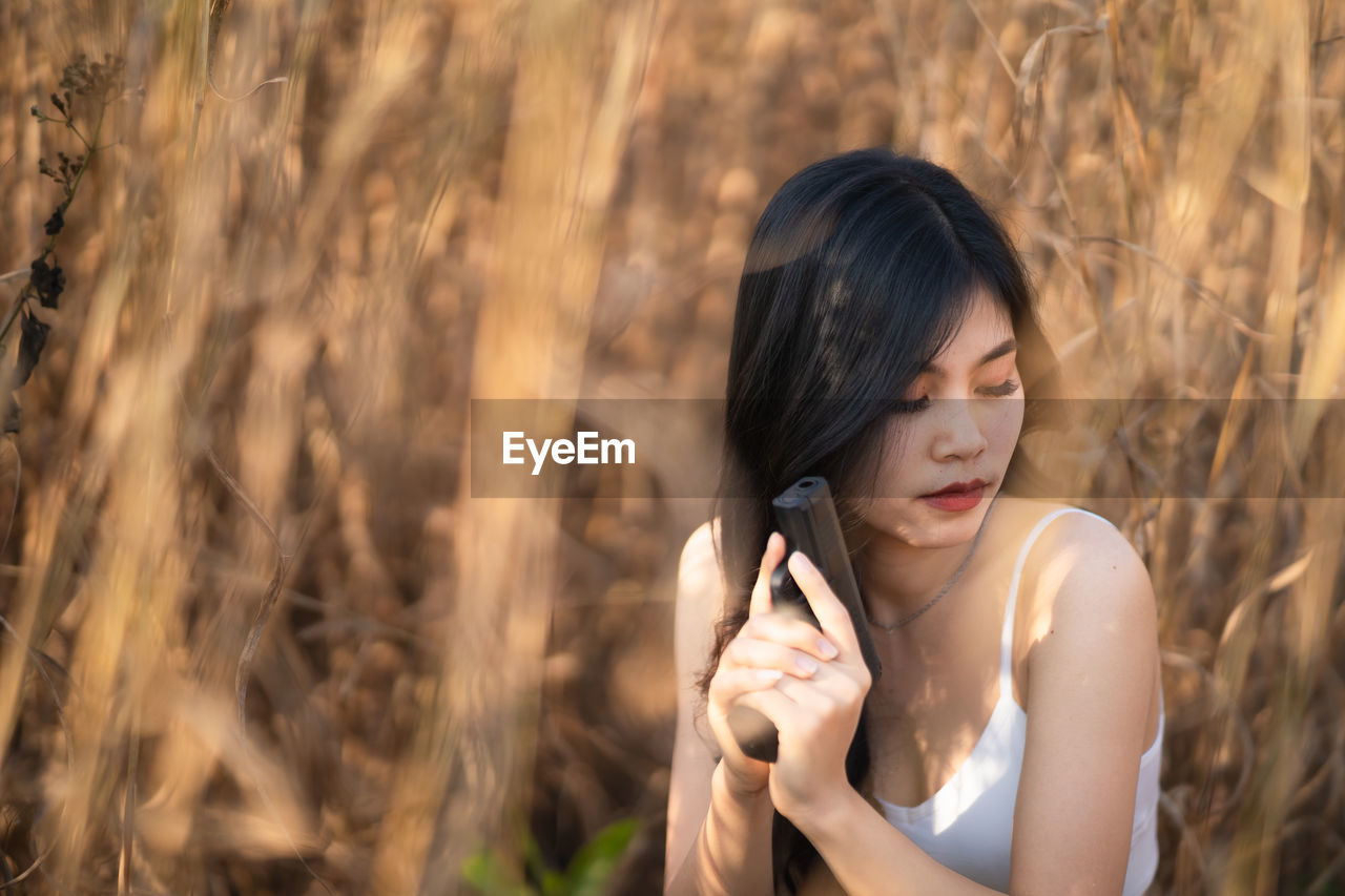 Young woman holding gun by plants