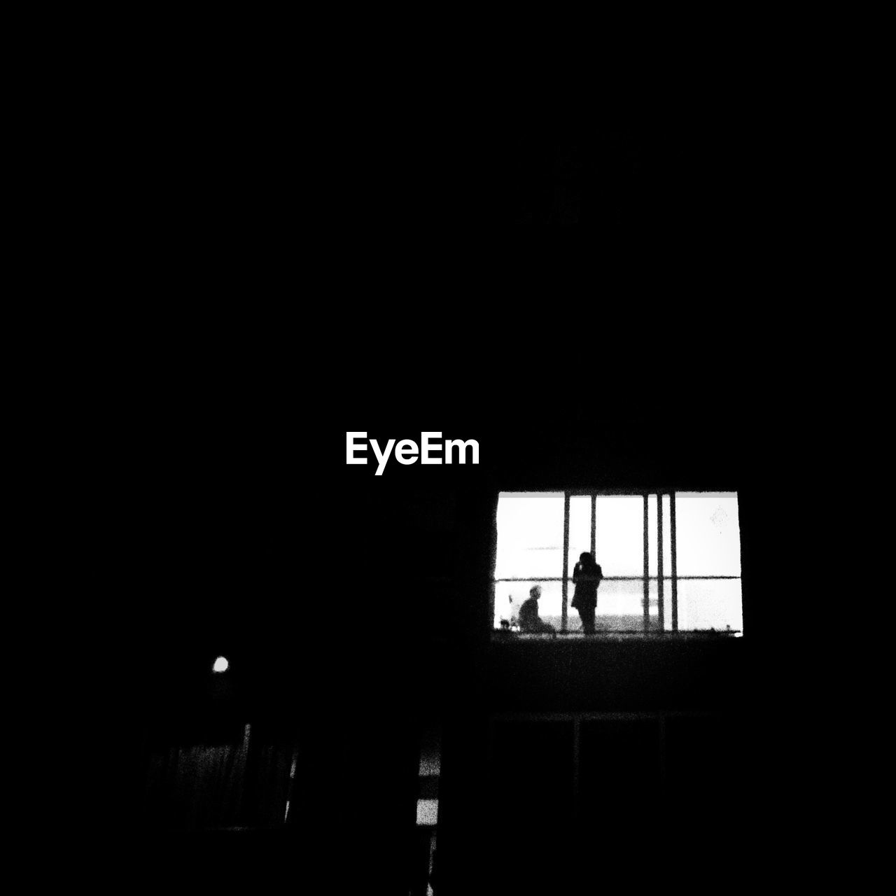 Silhouette of two people standing outside window