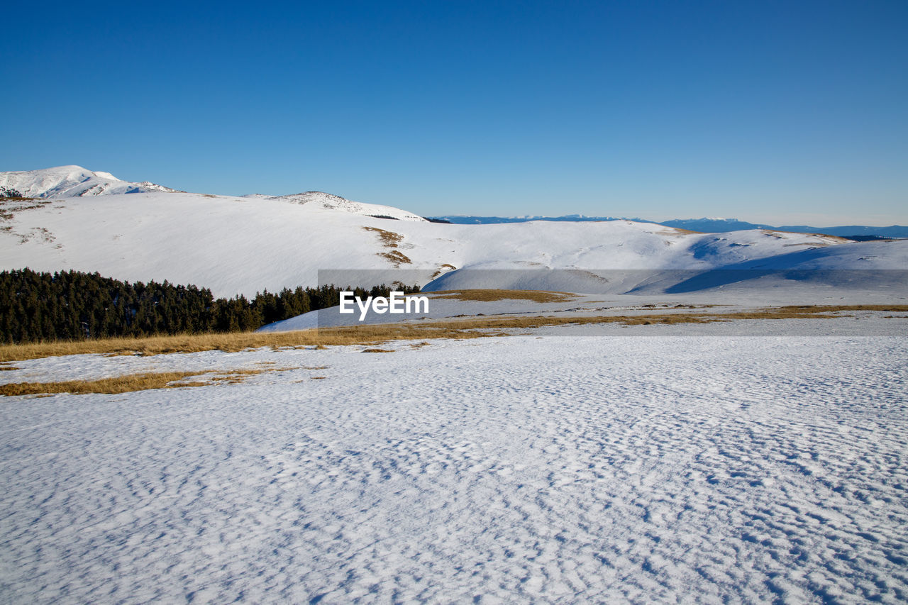 SNOW COVERED LAND AGAINST BLUE SKY