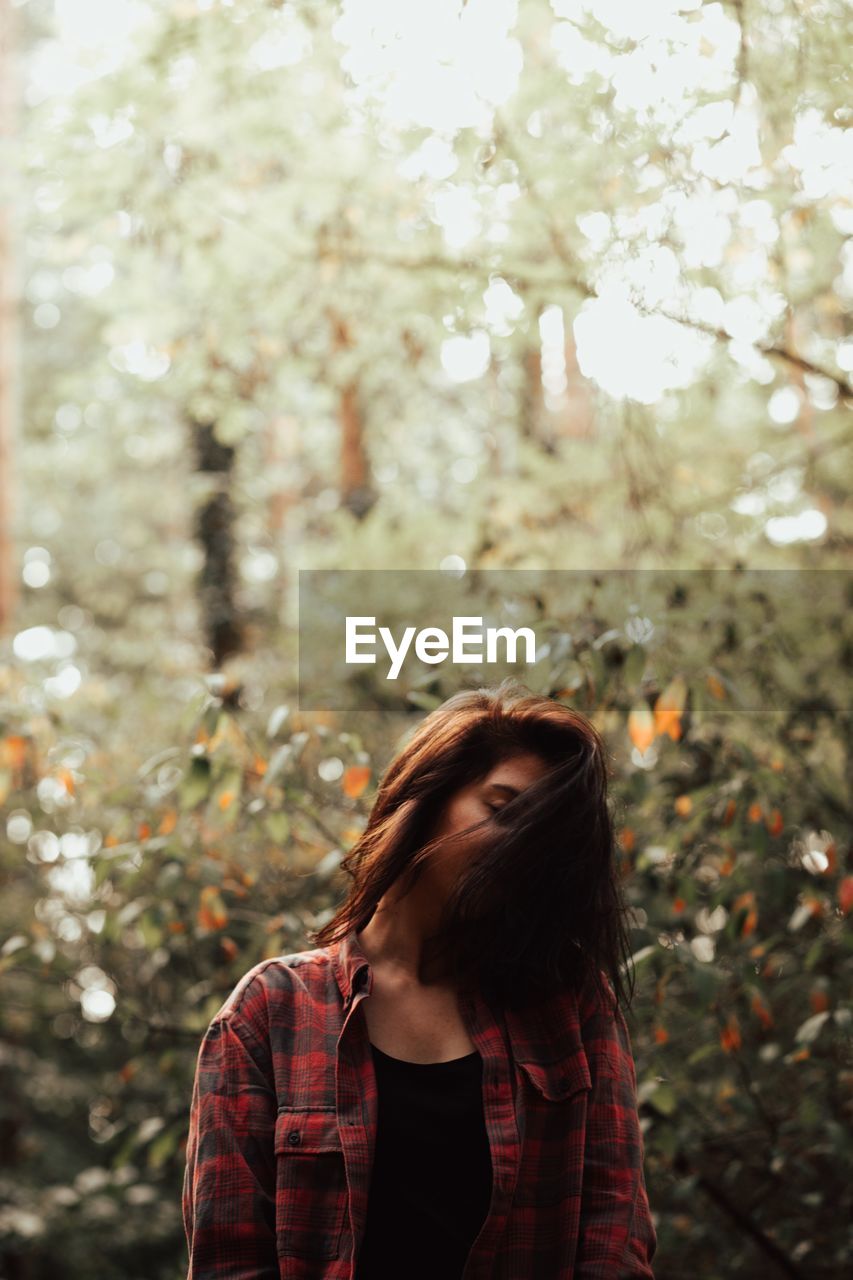 Young woman standing against plants