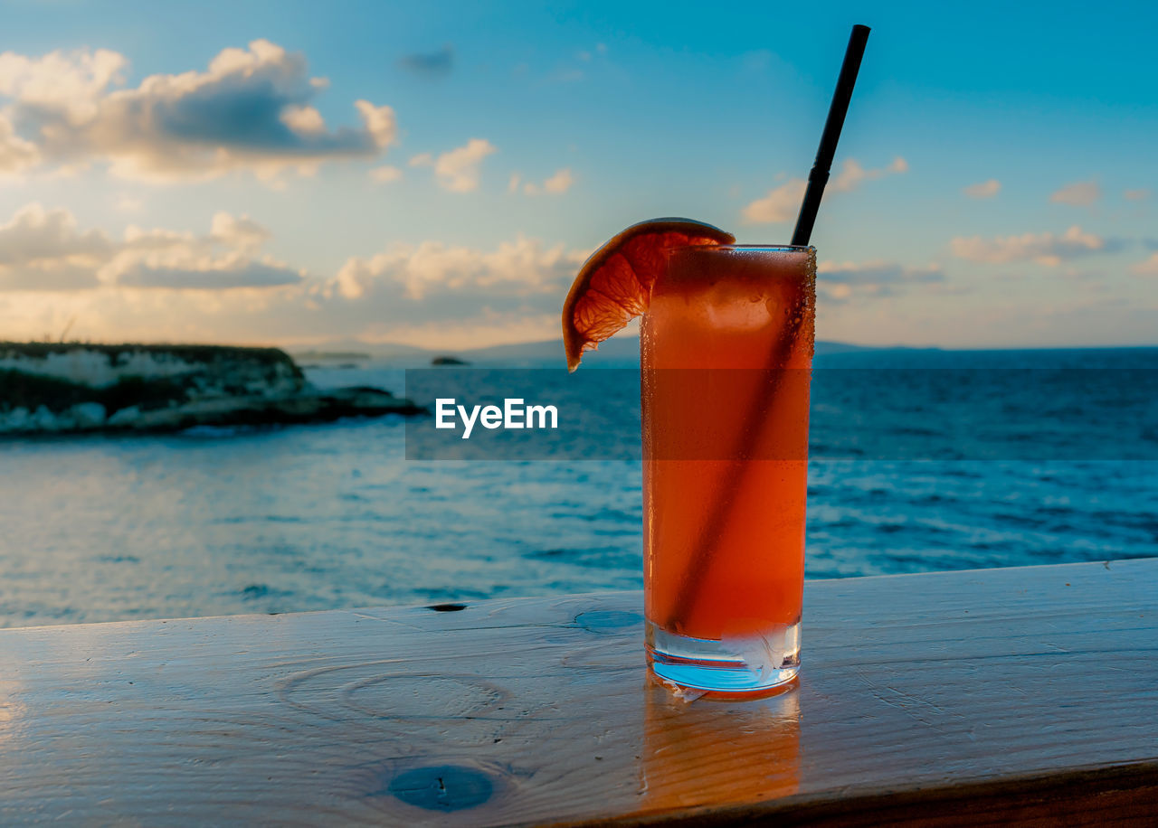 Close-up of cocktail on table at beach against sky in the summer.