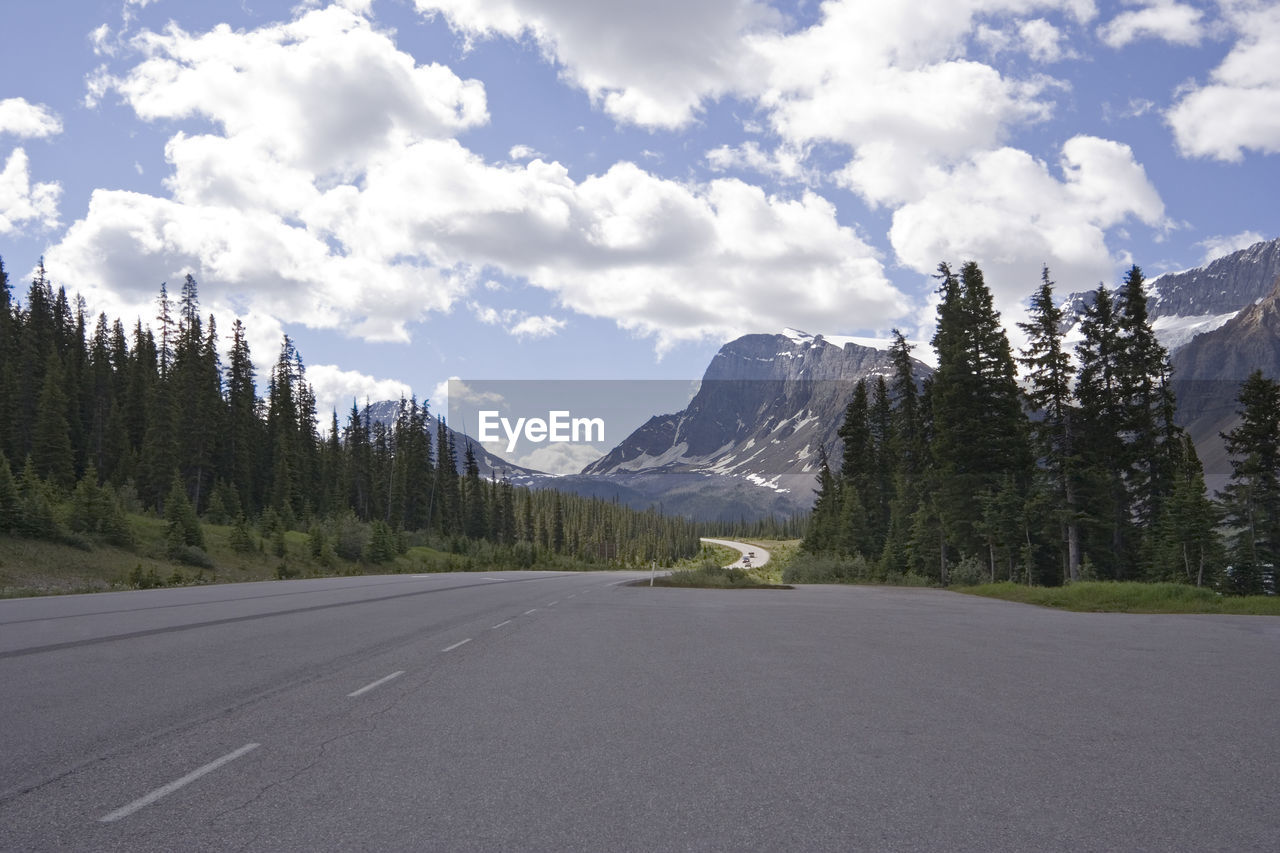 ROAD BY TREES AND MOUNTAINS AGAINST SKY