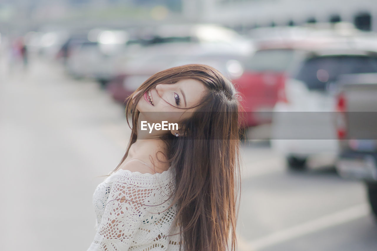 Beautiful young woman standing at parking lot