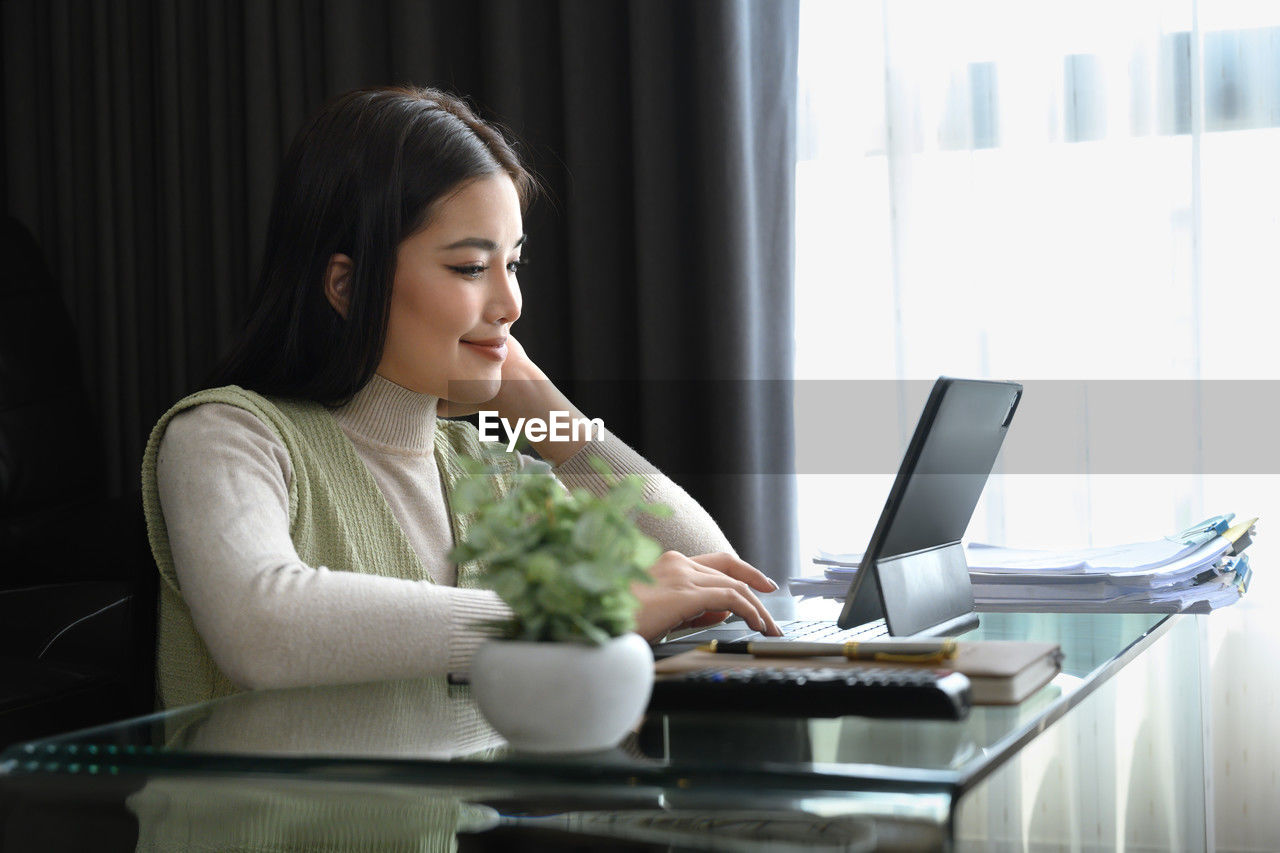 side view of young woman using mobile phone at home