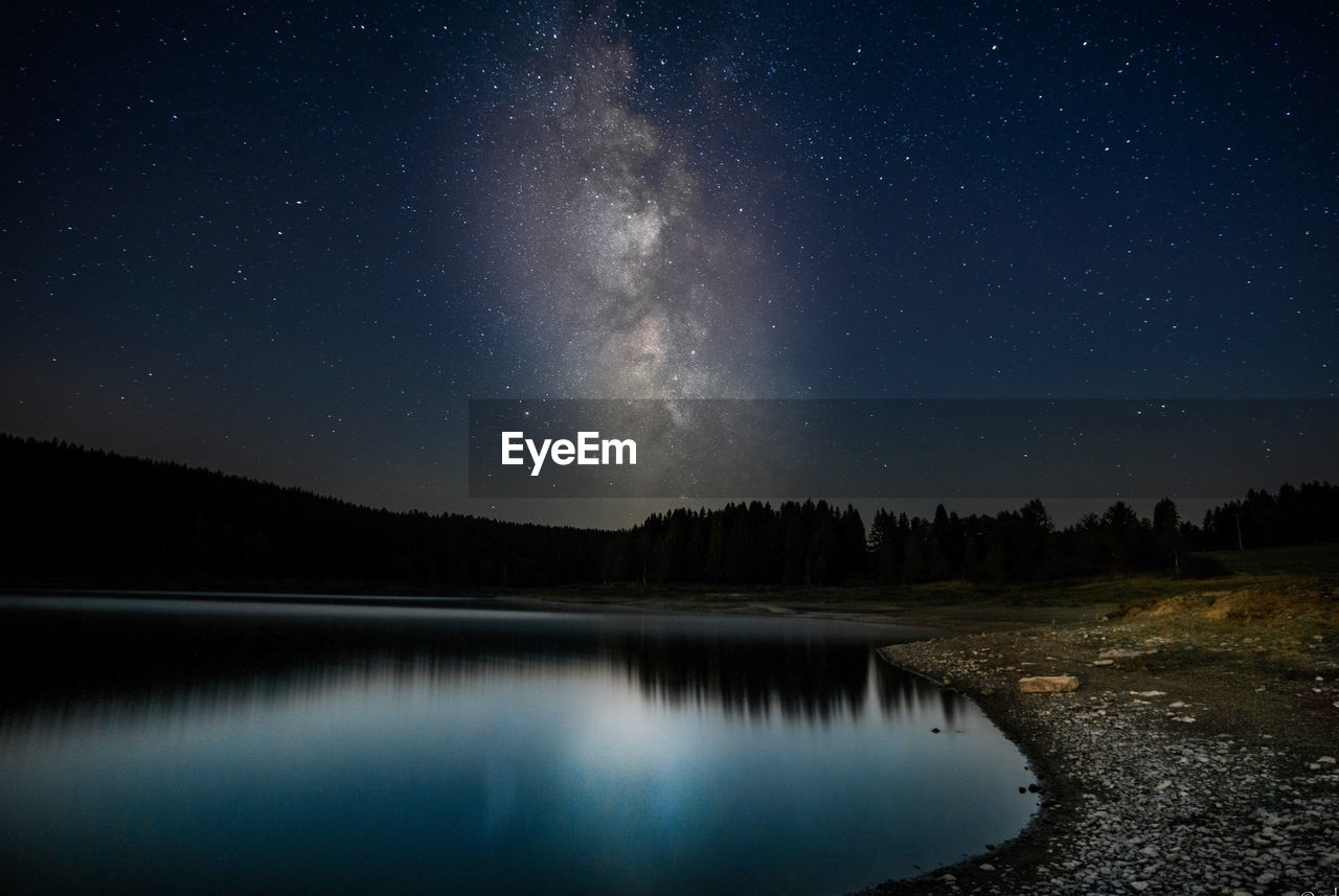 Scenic view of lake against sky at night