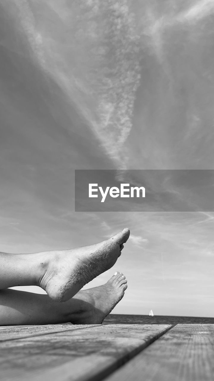 white, black and white, monochrome, monochrome photography, cloud, nature, sky, water, sea, relaxation, one person, wave, day, black, lying down, outdoors, ocean, adult, low section, hand, beauty in nature, tranquility, sunlight, leisure activity