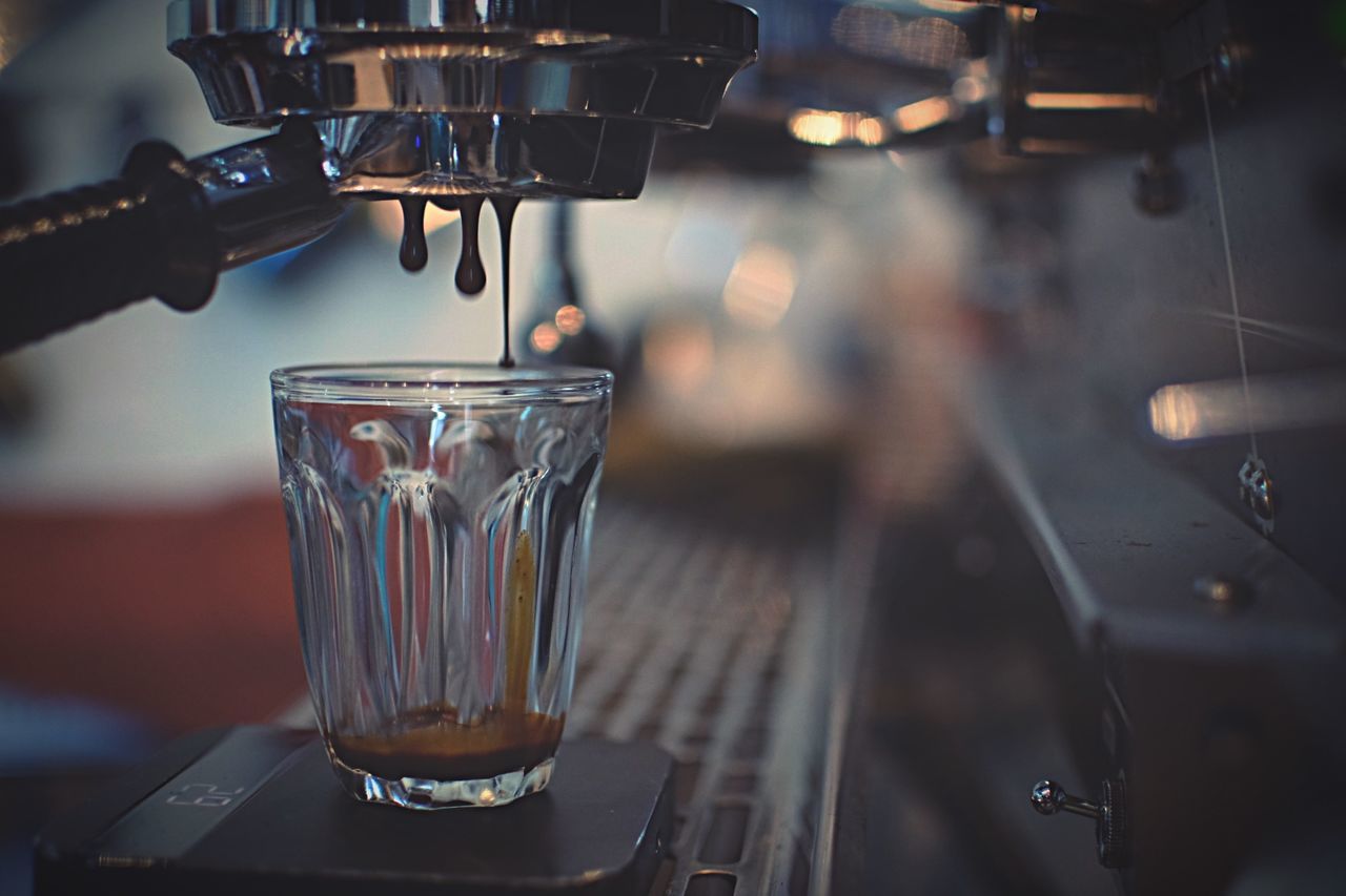 Close-up of coffee pouring into drinking glass at cafe