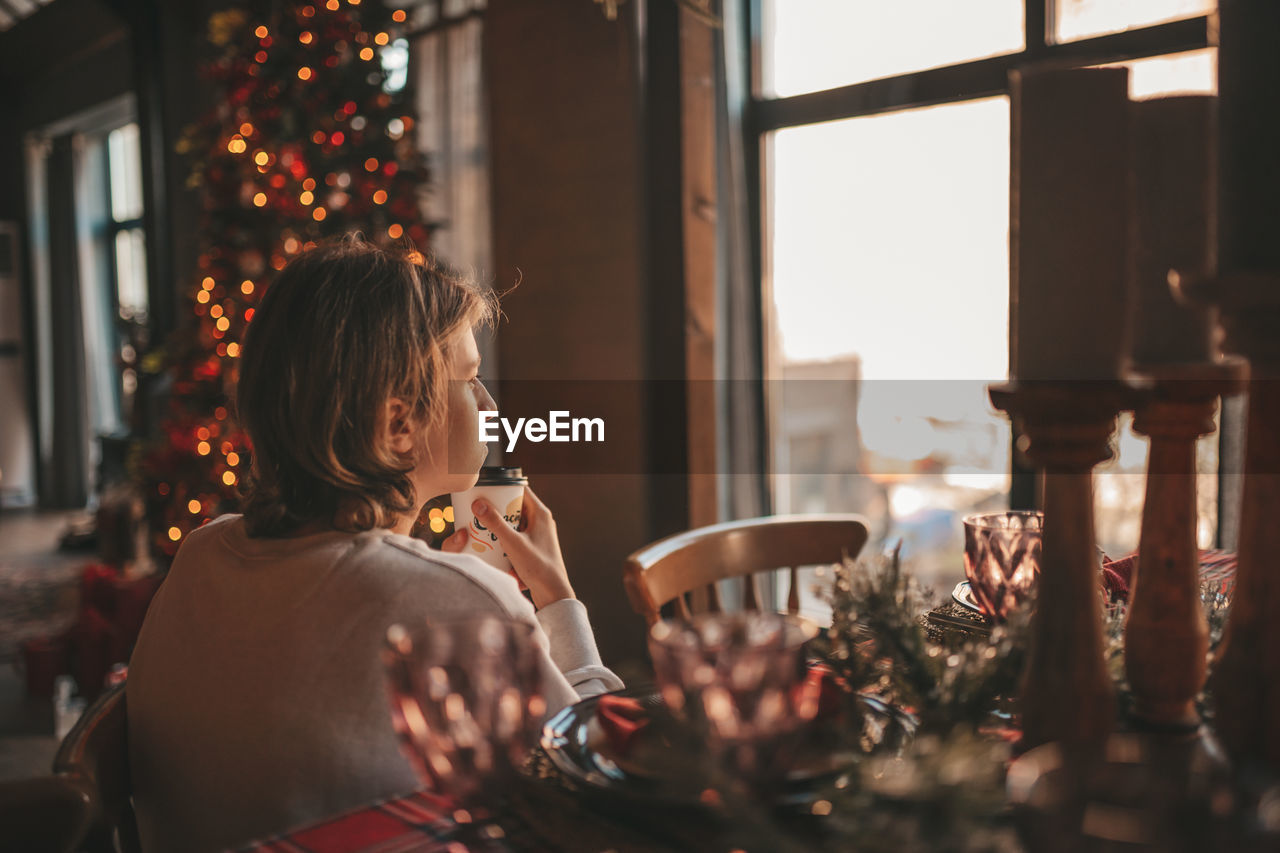 Portrait of candid authentic smiling handsome boy teenager using mobile phone at xmas home interior