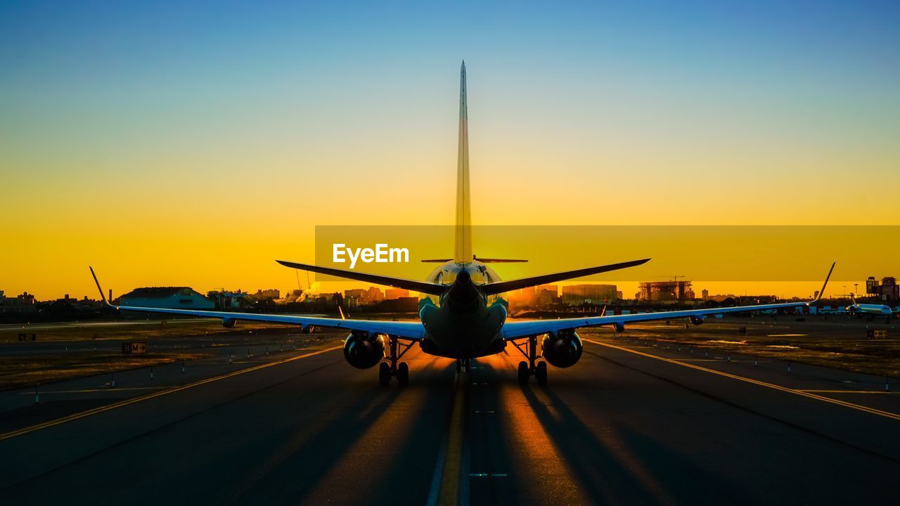 Airplane flying over road at sunset